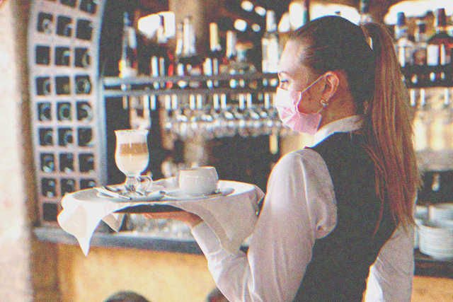 Masked waitress holding a tray | Photo: Shutterstock