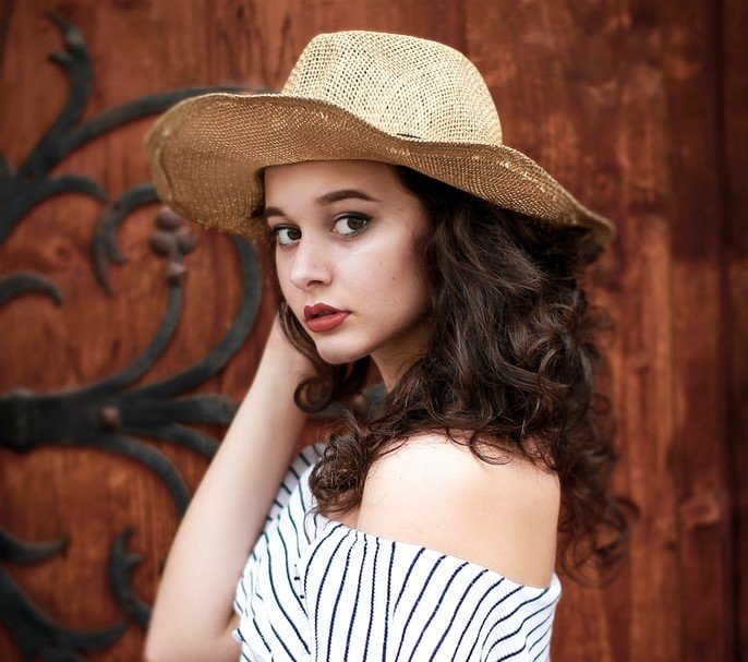 Hermosa joven usando un sombrero de mimbre. | Foto: Unsplash