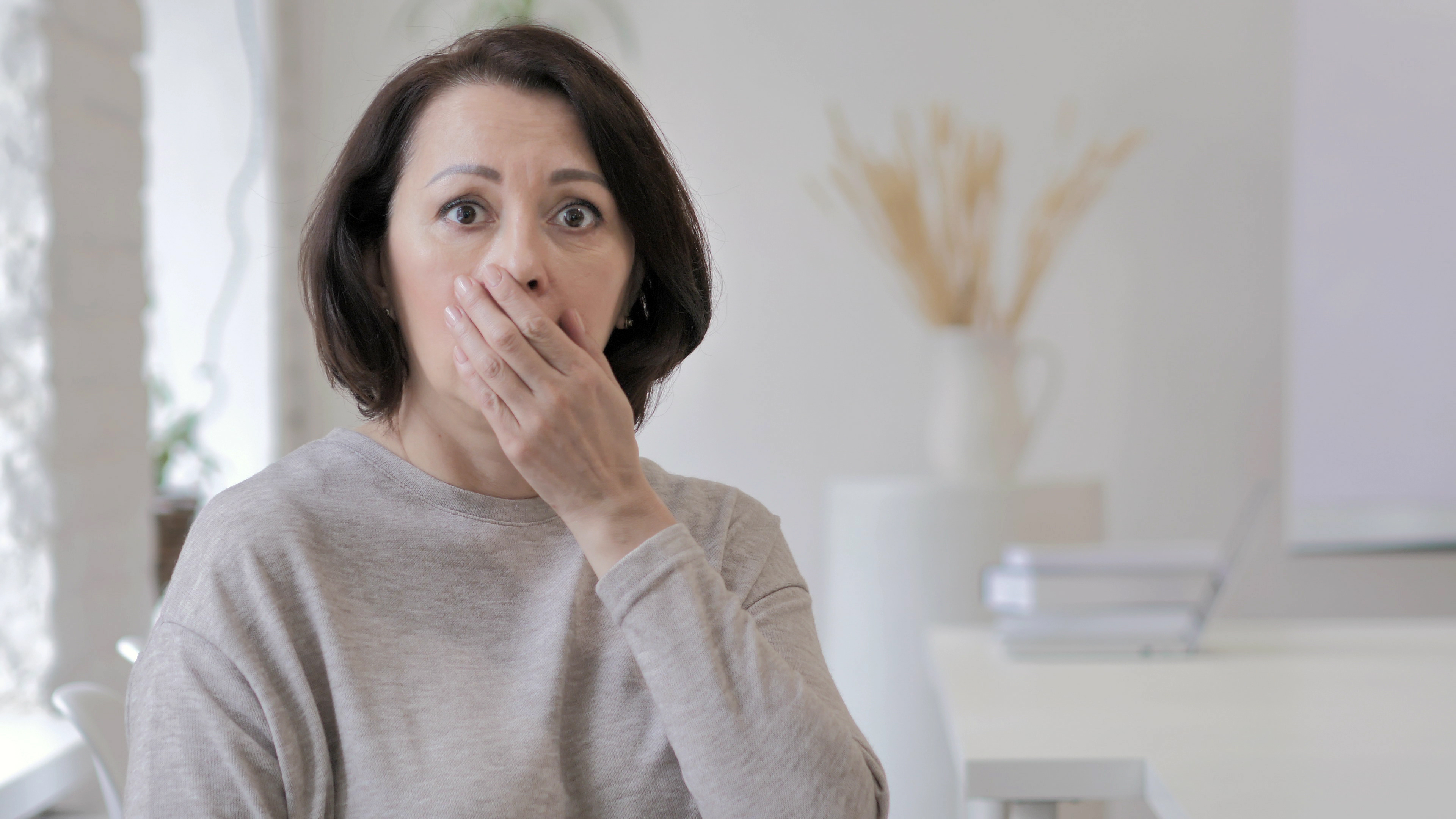 A shocked woman with her hand on her mouth | Source: Shutterstock