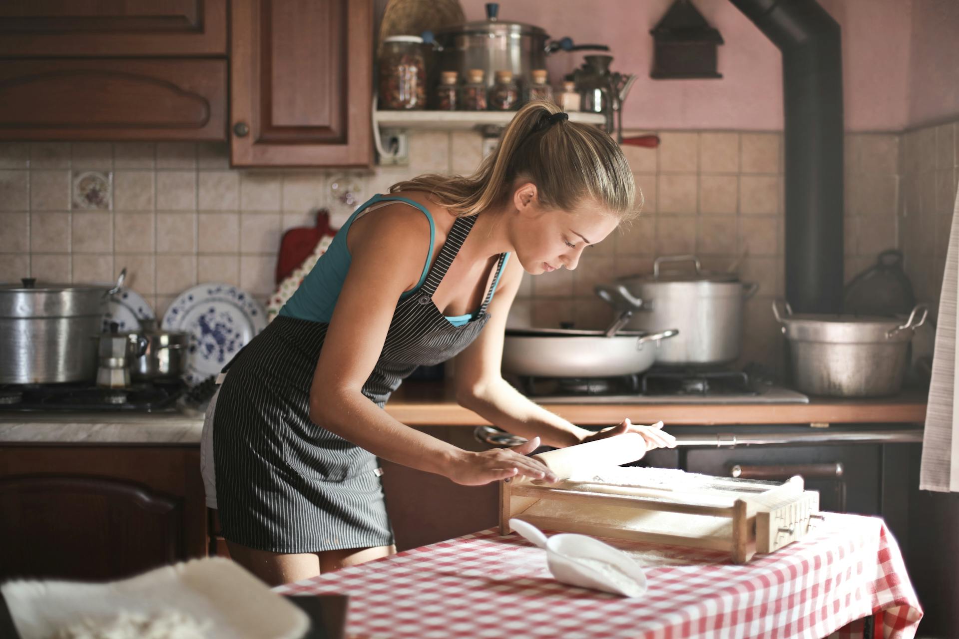 A young woman rolling dough for baking in kitchen | Source: Pexels