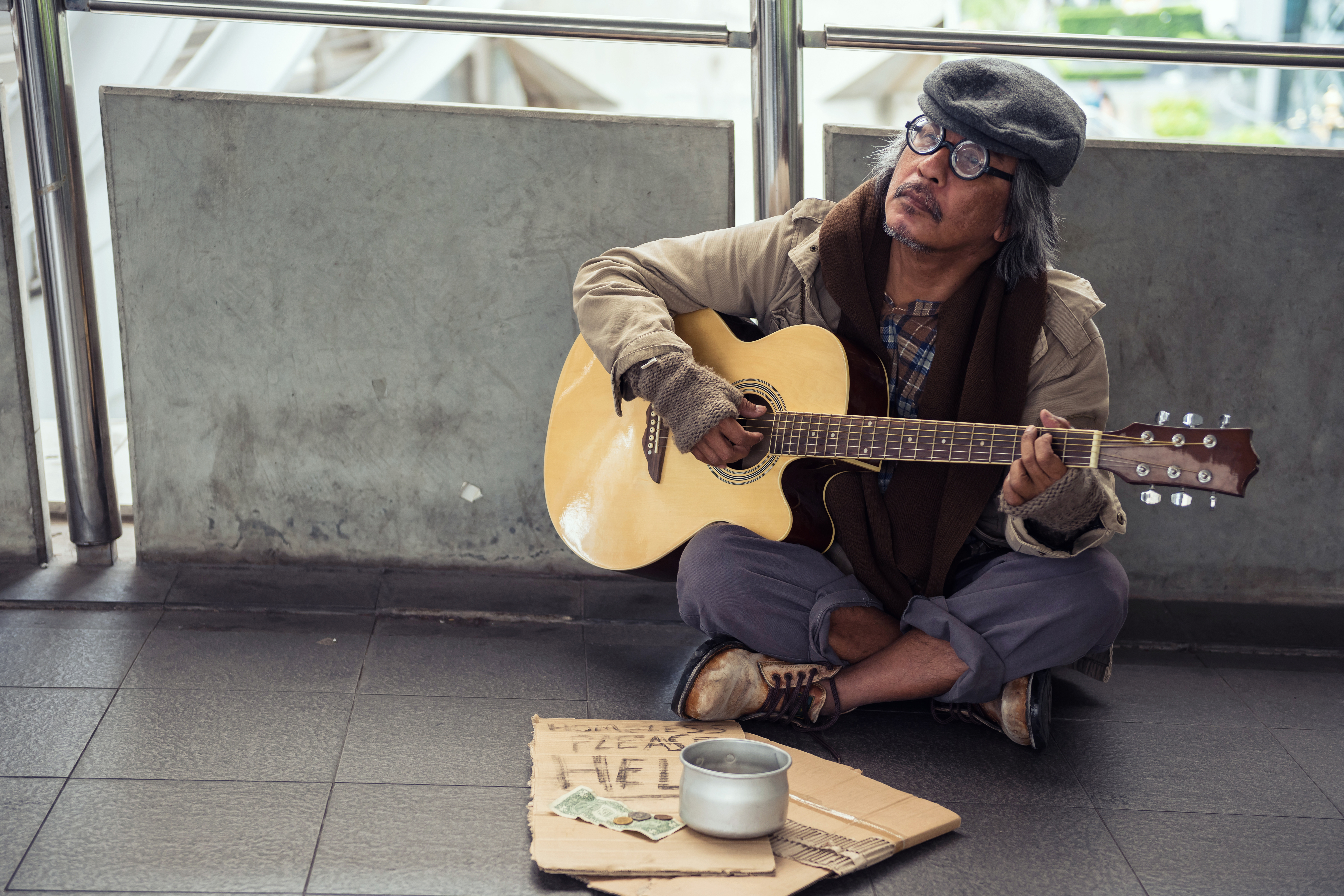 Old beggar or senior Homeless man playing guitar. | Source: Shutterstock