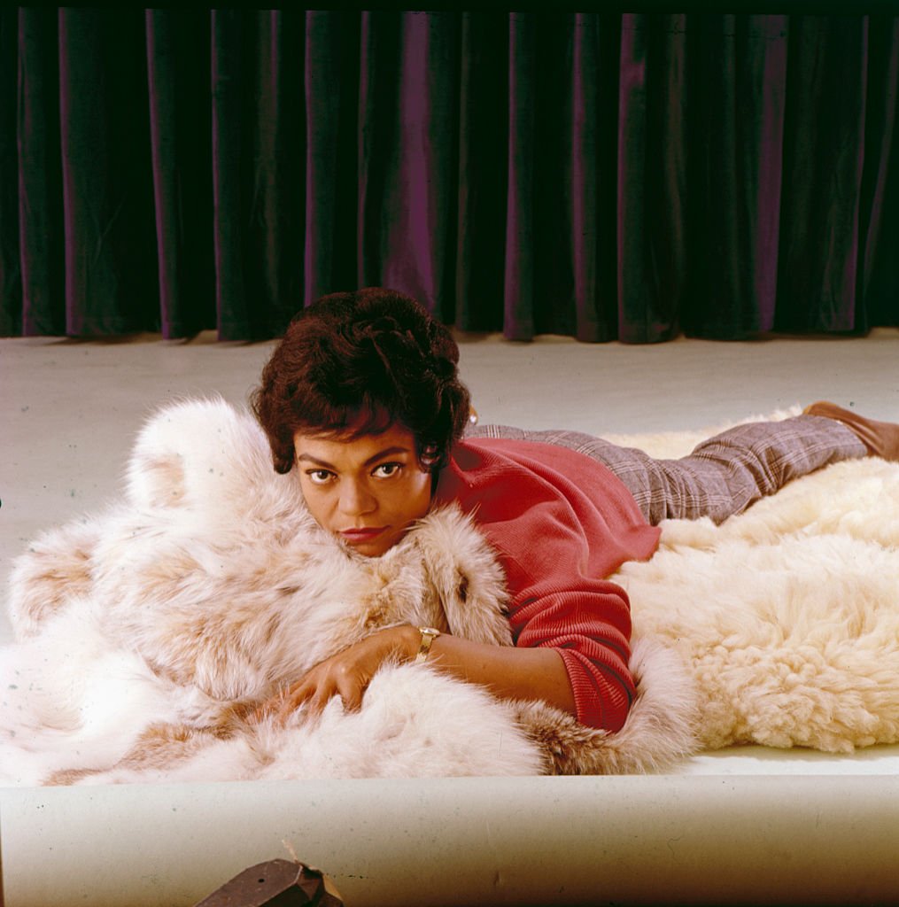 Iconic actress and singer Eartha Kitt lying on her belly with a rug underneath during a photo session in 1965. | Source: Getty Images