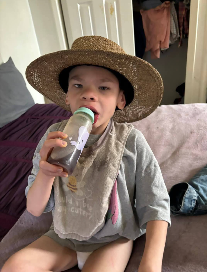 Hershall Creachbaum wears an oversized hat while drinking from a bottle, from a post dated July 13, 2025 | Source: Facebook/MissyRowlandCreachbaum