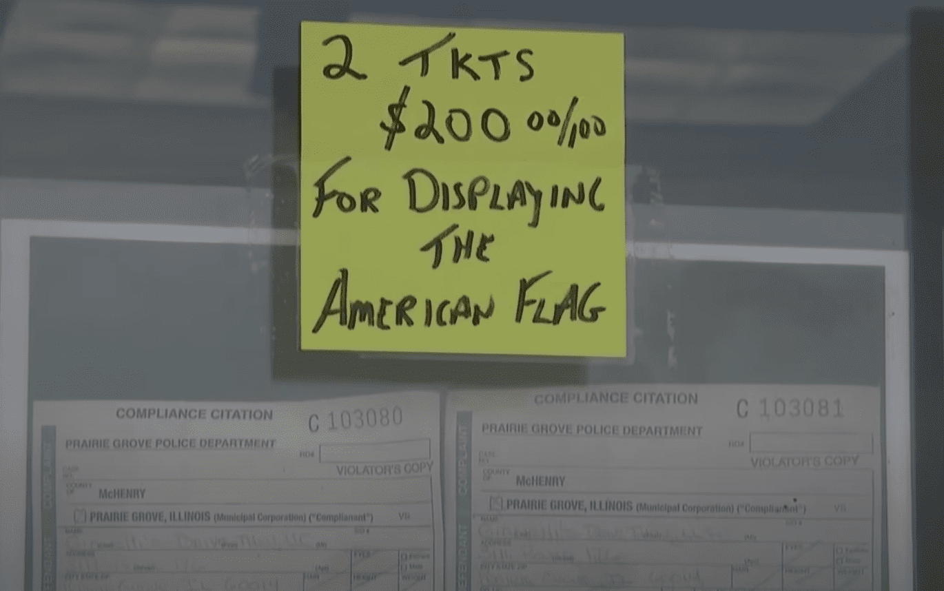 A business owner taped two tickets to the front door of his shop to notify customers about the citation he received for flying the American flag | Photo: Youtube/FOX 32 Chicago