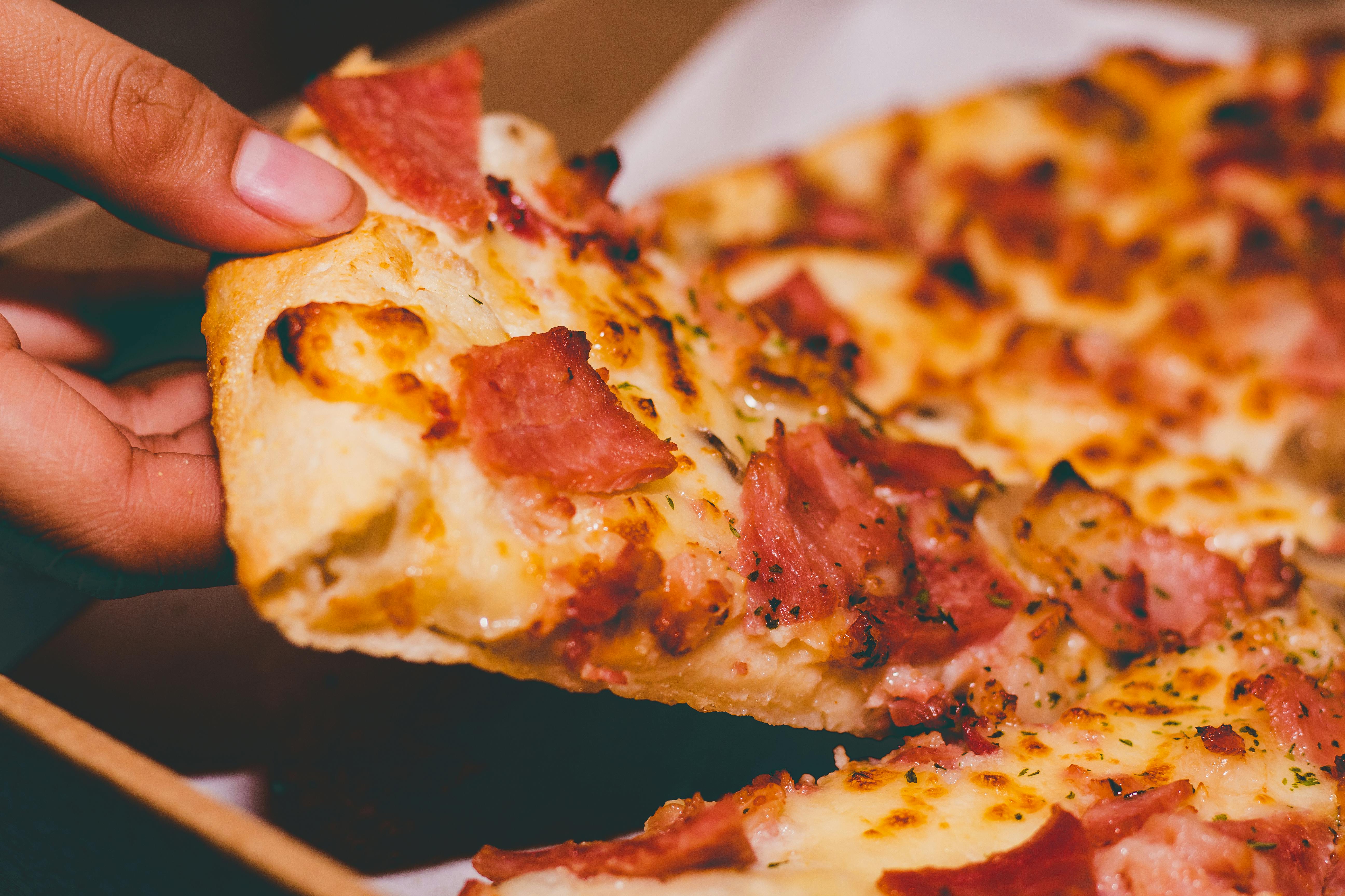 A person holding a slice of pizza | Source: Pexels