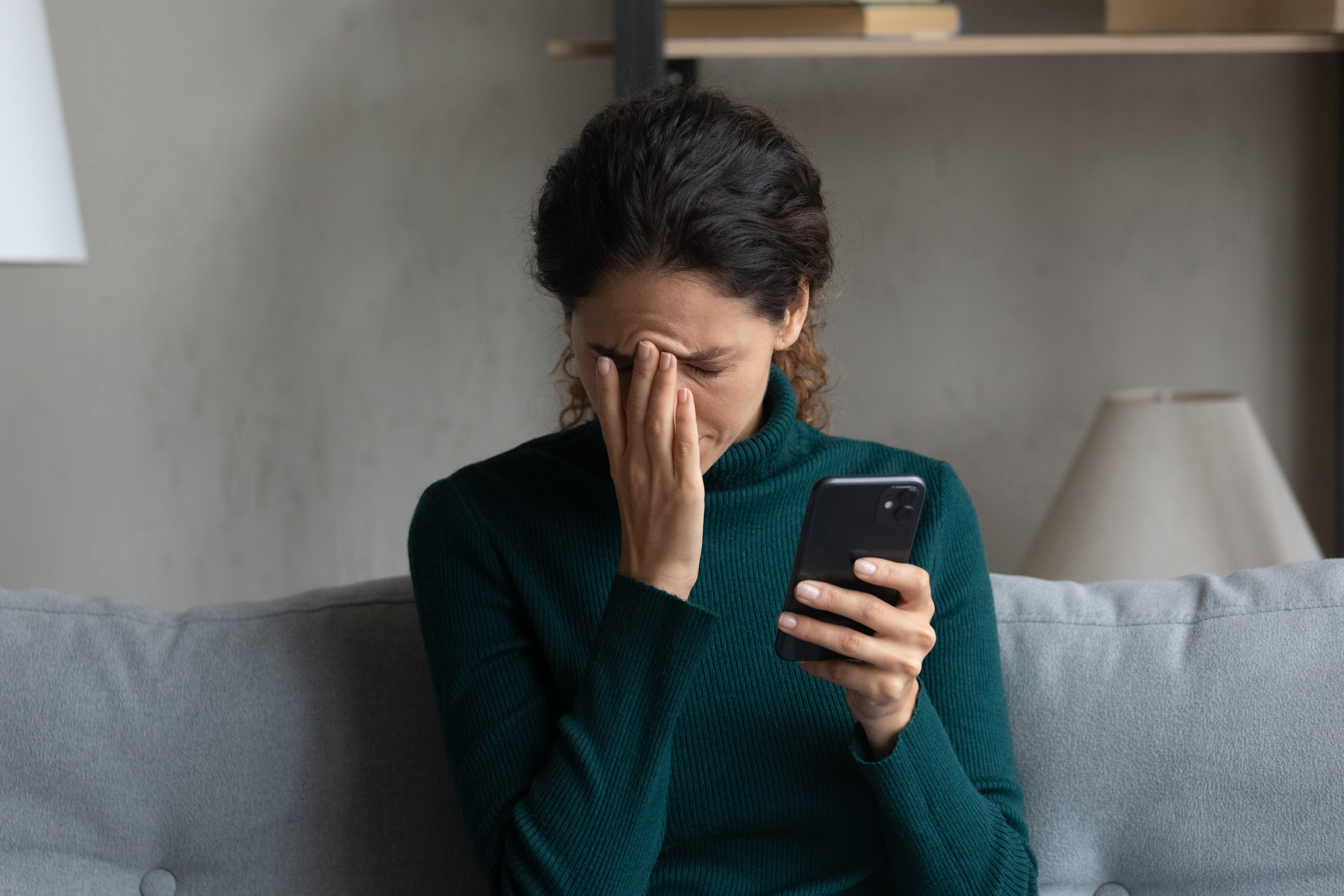 A distraught woman holding her phone | Source: Shutterstock