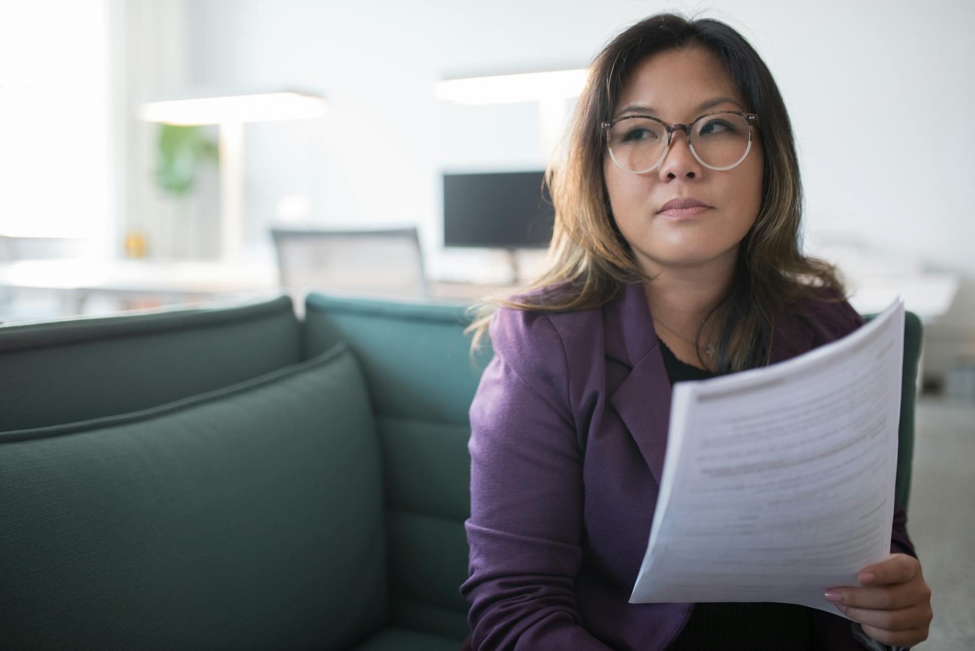 A woman thinking while holding a set of documents | Source: Pexels
