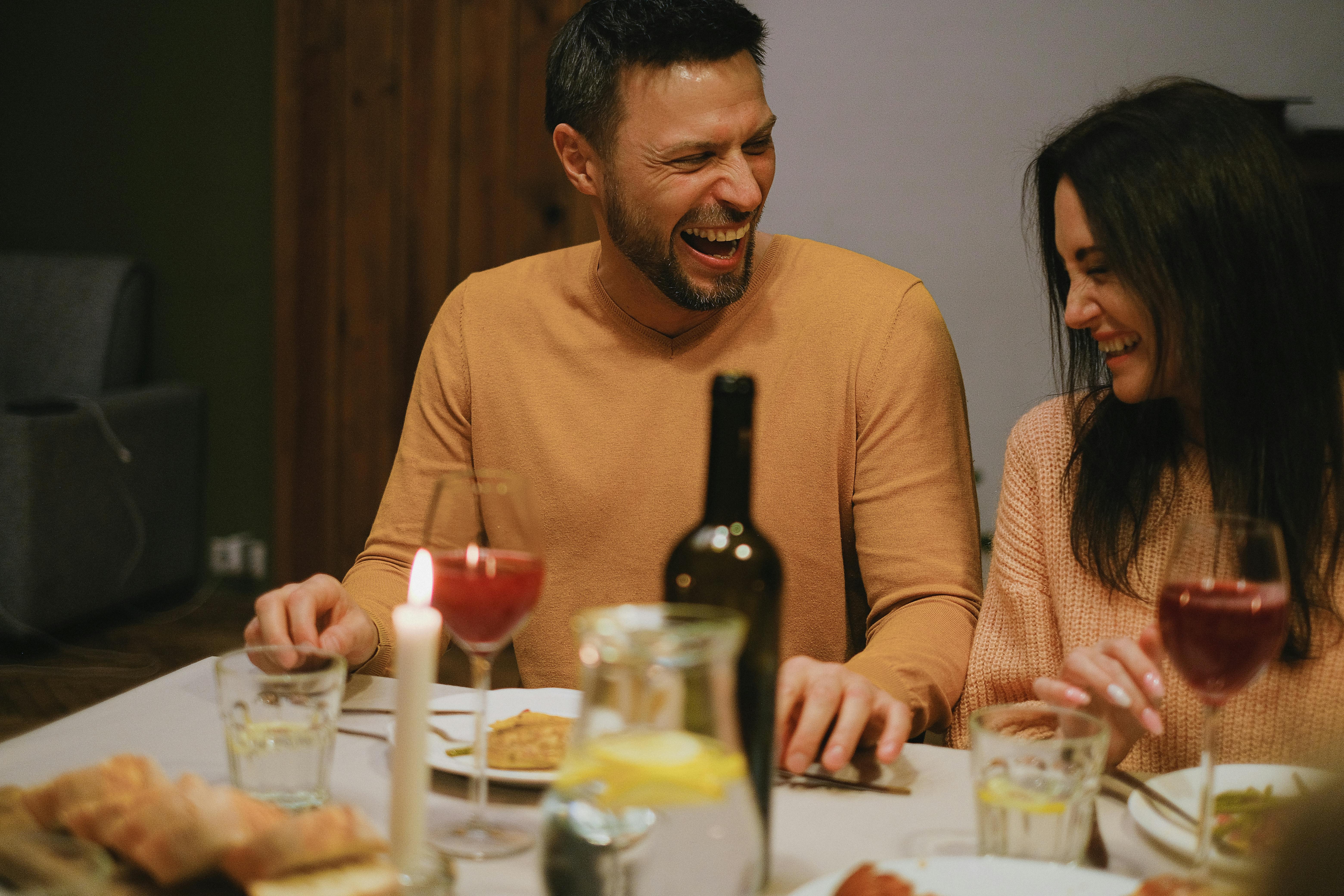 A couple laughing at the dinner table | Source: Pexels