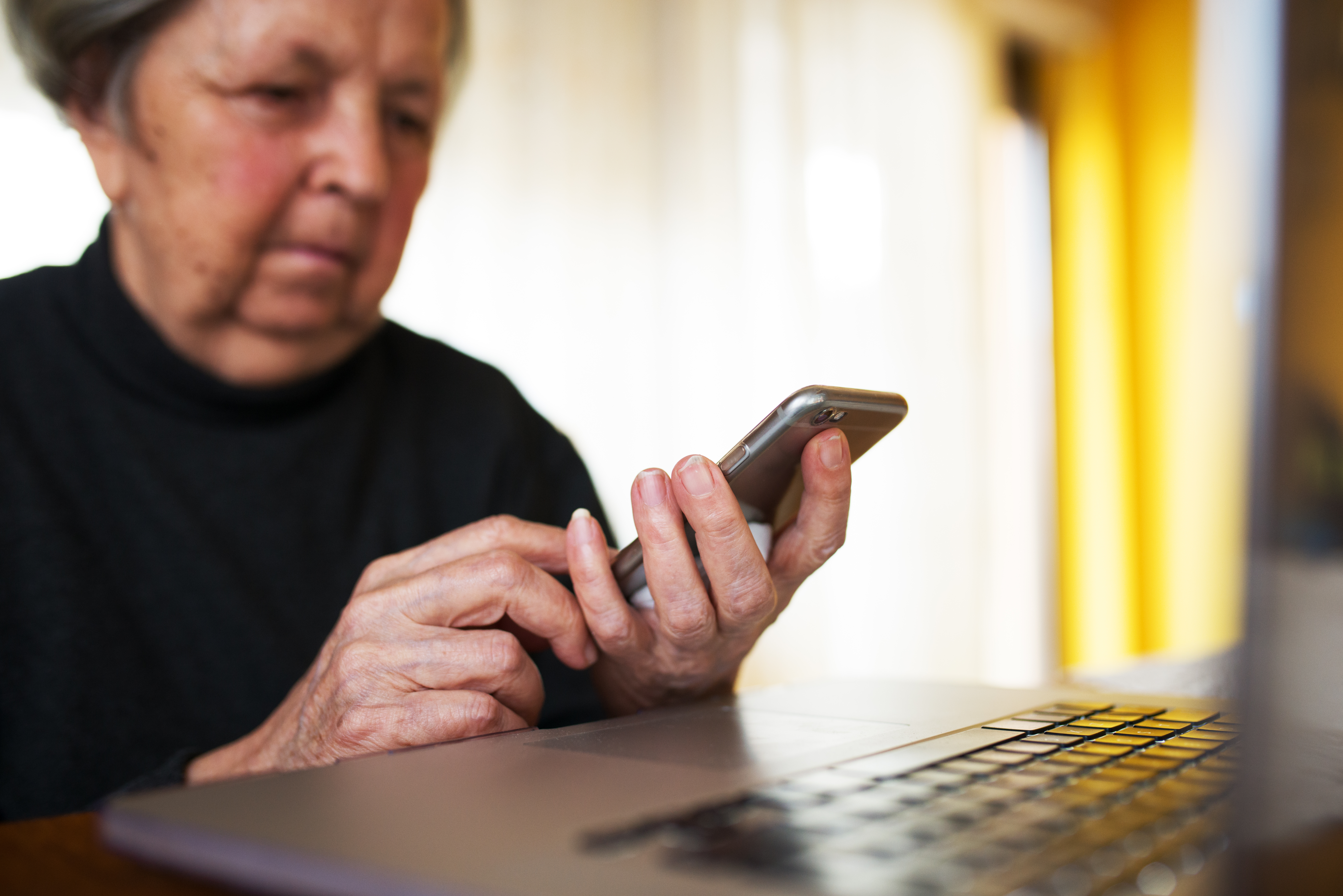 A senior woman using a smartphone and laptop at home | Source: Shutterstock