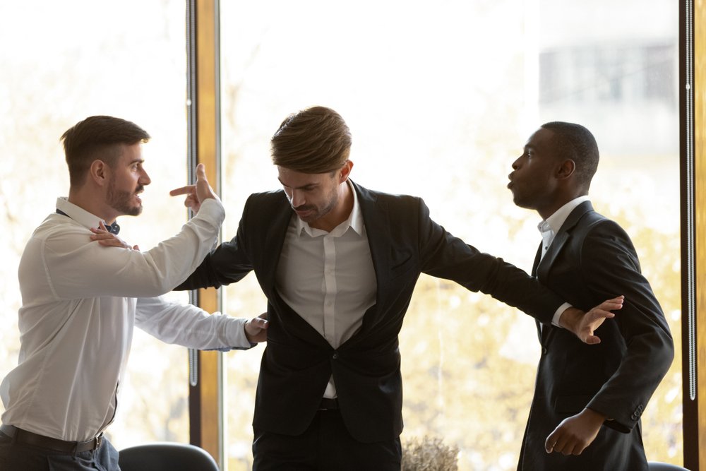 A photo of a man trying to stop two other men from fighting | Photo: Shutterstock