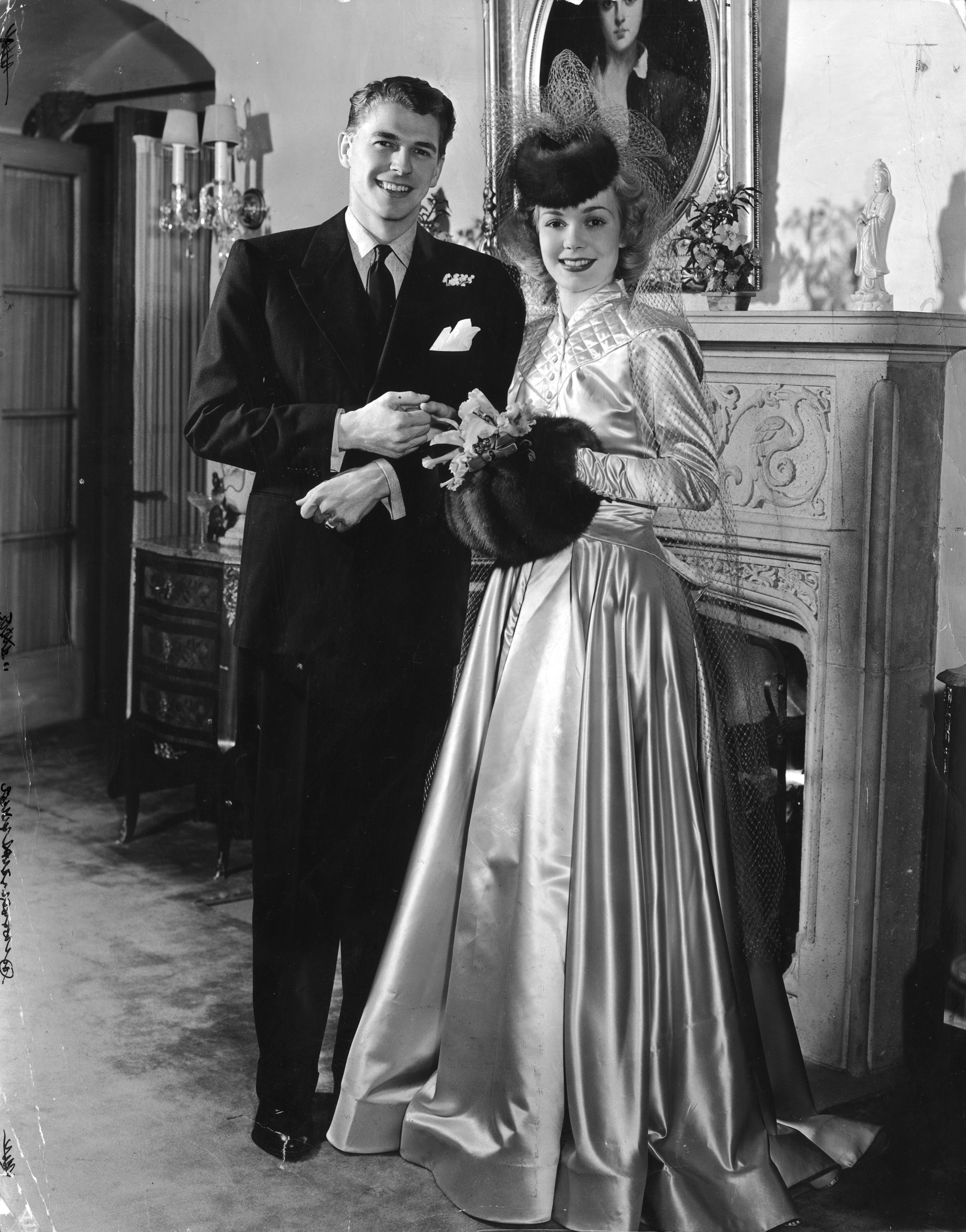 Portrait of Ronald Reagan with his first wife, Jane Wyman holding hands in front of a stone fireplace on their wedding day on January 25, 1940 | Source: Getty Images
