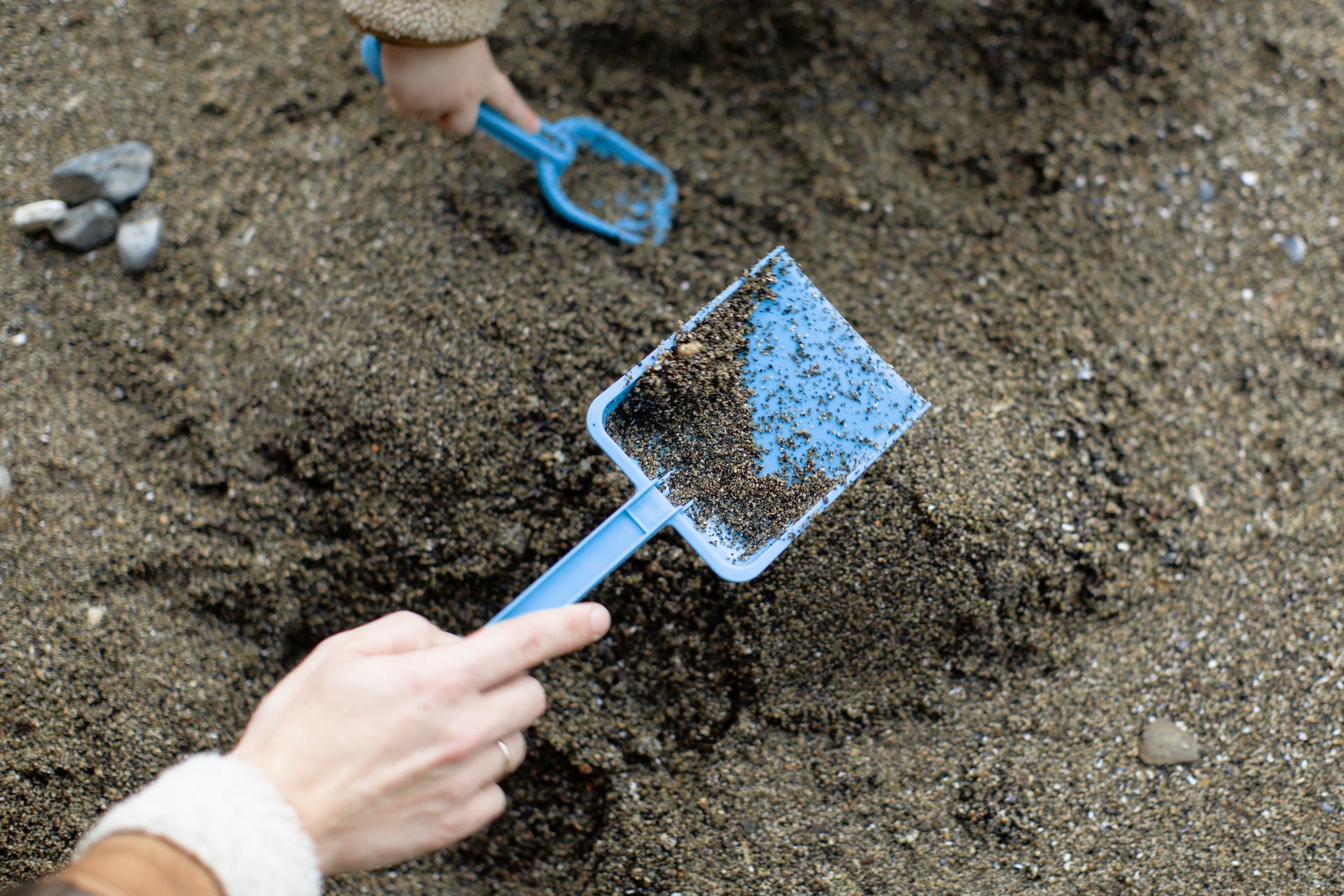 A person and a child holding shovels in sand | Source: Pexels