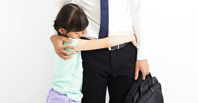 Little girl hugging her working dad | Photo: Shutterstock.com