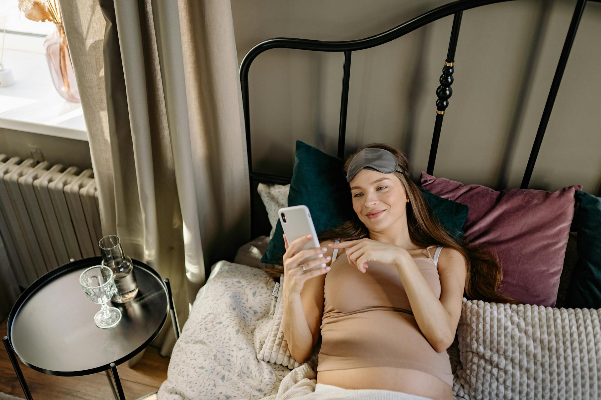 A woman scrolling on her phone in bed | Source: Pexels