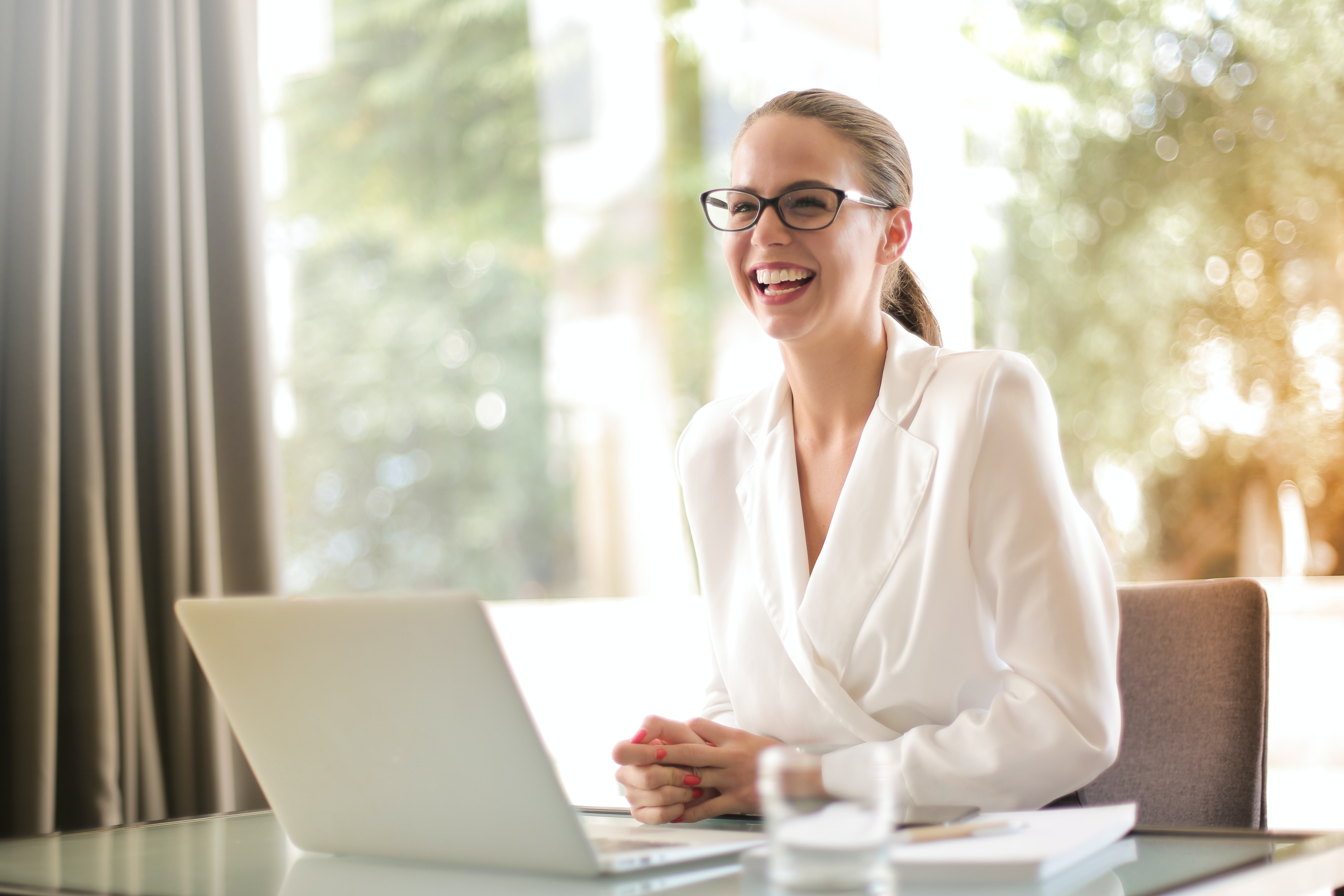 A working woman laughing with a laptop in front of her | Source: Pexels