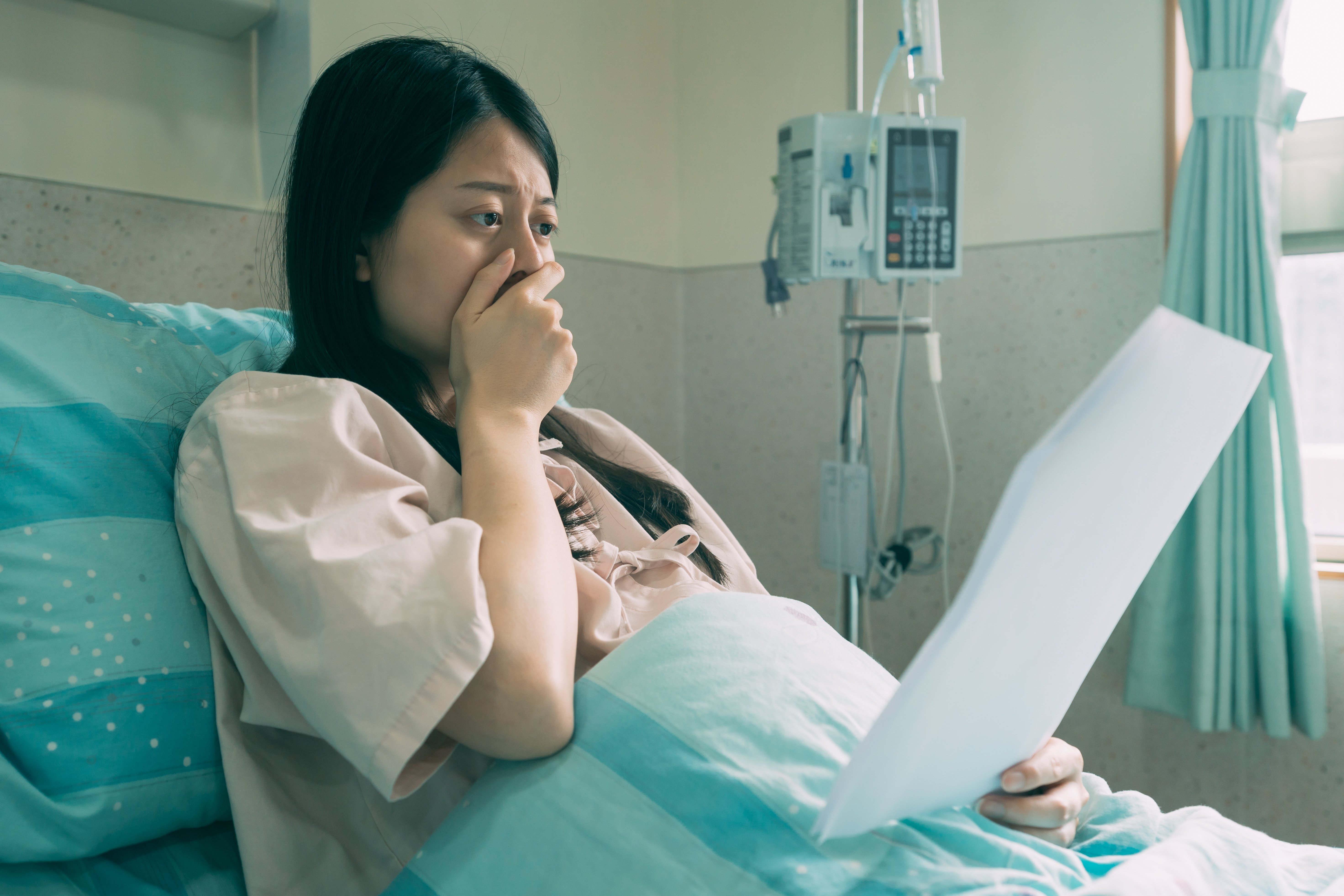 Mujer sorprendida leyendo carta en cama de hospital. | Foto: Shutterstock