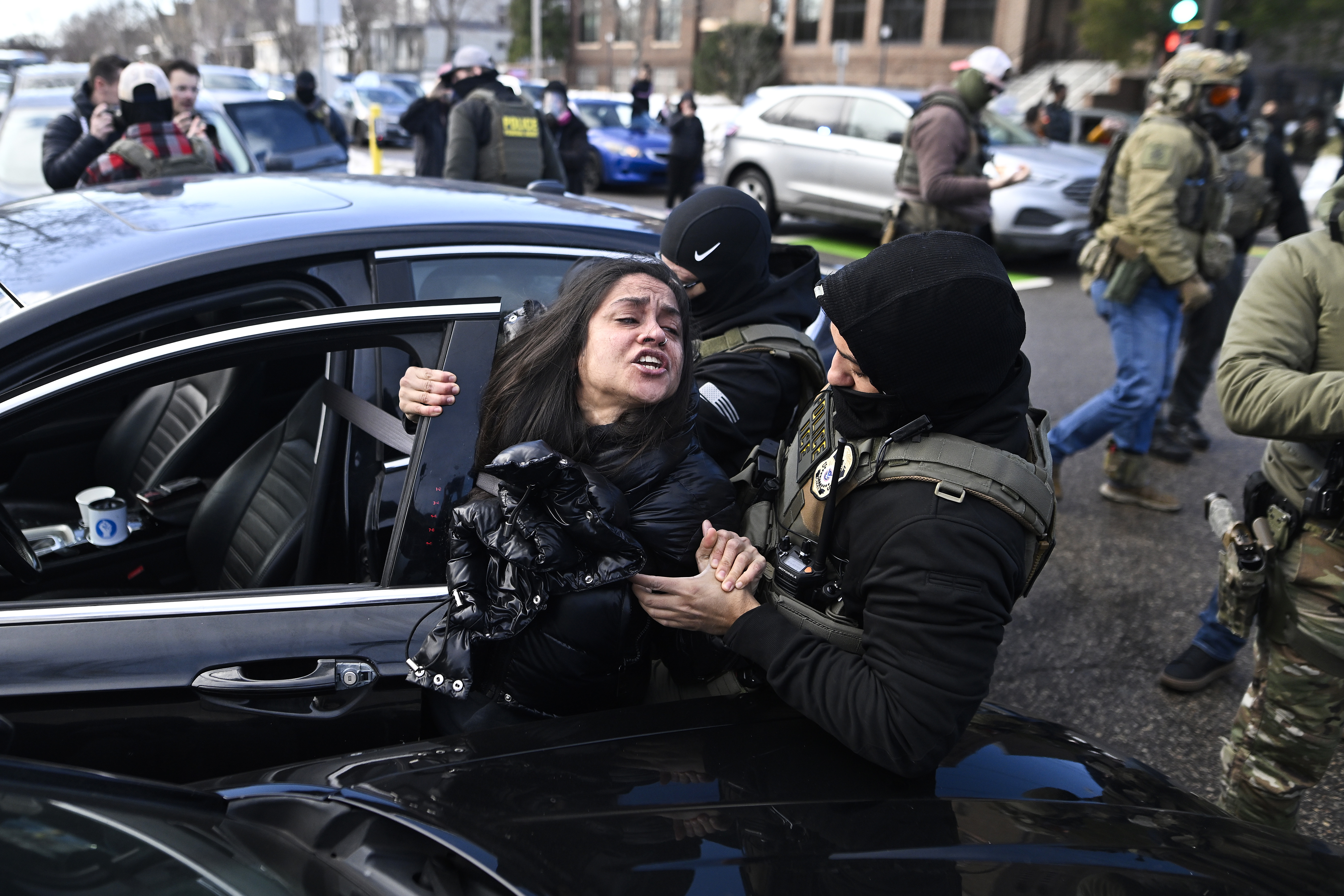 ICE agents pull a woman from a car before detaining her on January 13, 2026 in Minneapolis, Minnesota. | Source: Getty Images