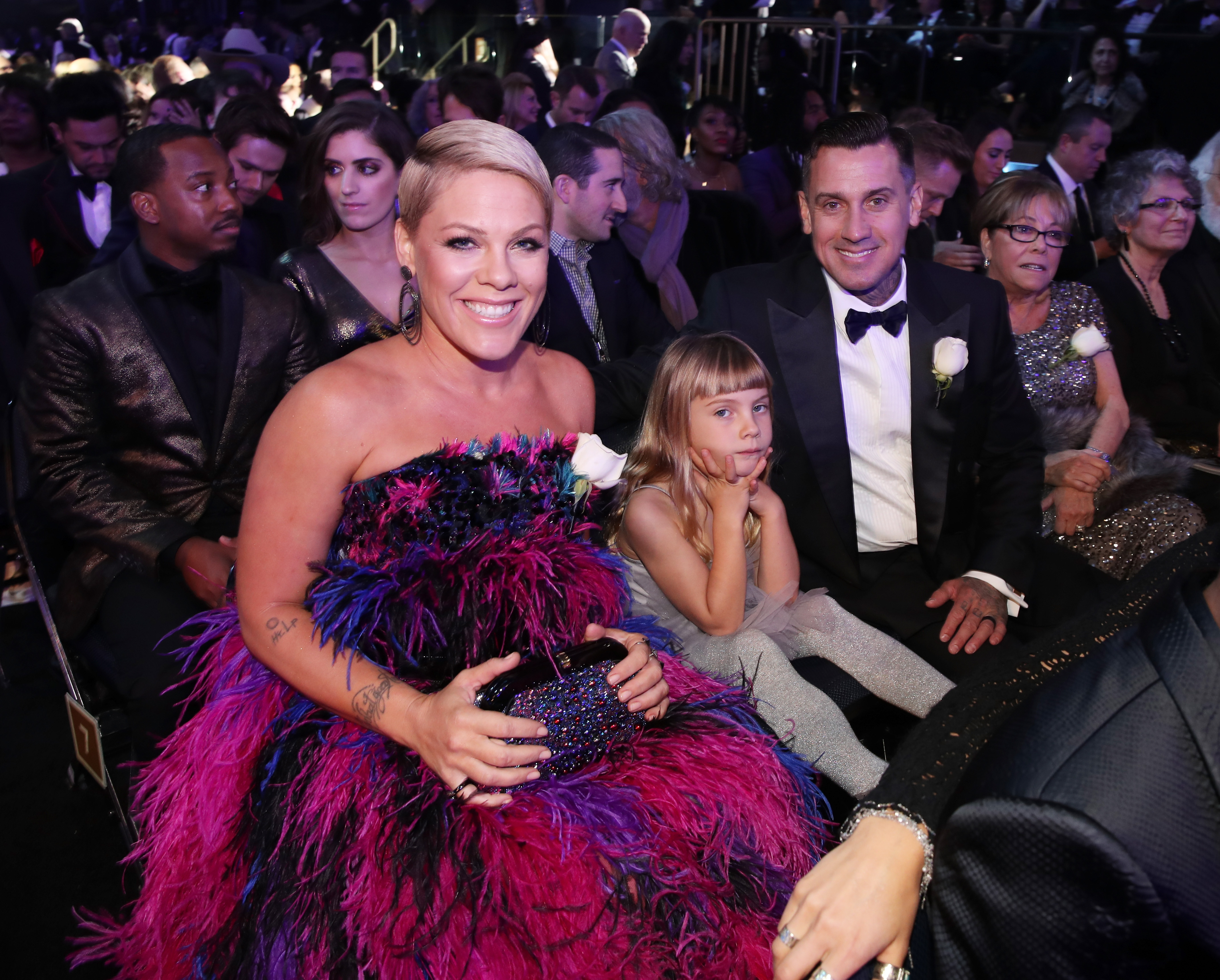 Pink sits with Willow Sage Hart and Carey Hart at the 60th Annual Grammy Awards on January 28. Pink wears a vivid feathered gown while Willow sits between her parents in a soft gray ensemble.