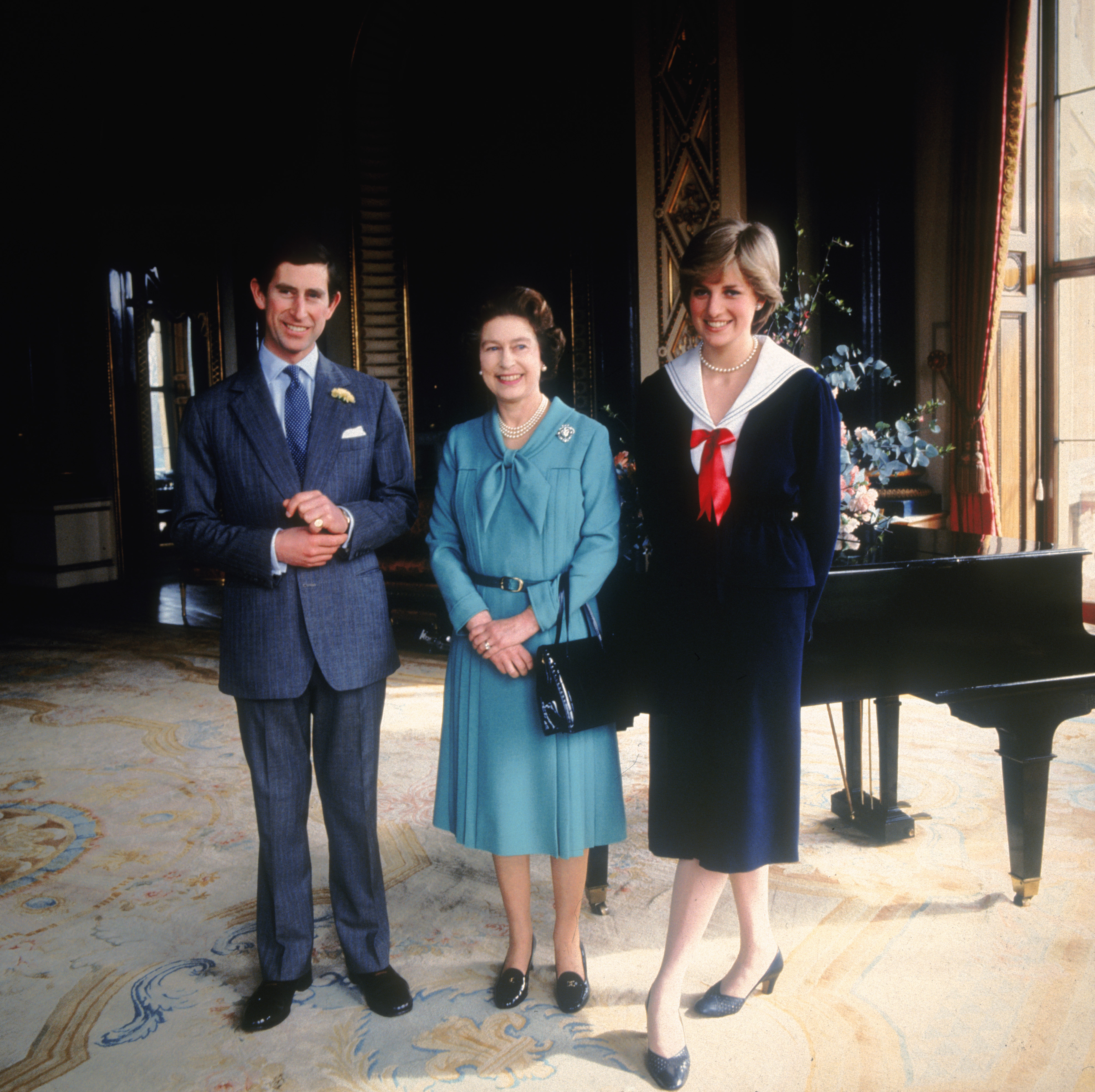 In a formal portrait taken at Buckingham Palace on 7 March 1981, Prince Charles stands beside his fiancée at the time, Lady Diana Spencer, with Queen Elizabeth II positioned between them, the trio smiling softly as they mark the early days of a relationship that would soon captivate the world.