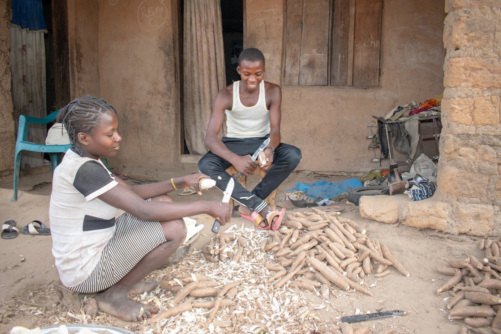Afrikanische Frauen und Kinder bei der Verarbeitung von Maniokmehl (Garri) in einer ländlichen Gemeinschaft. I Quelle: Shutterstock