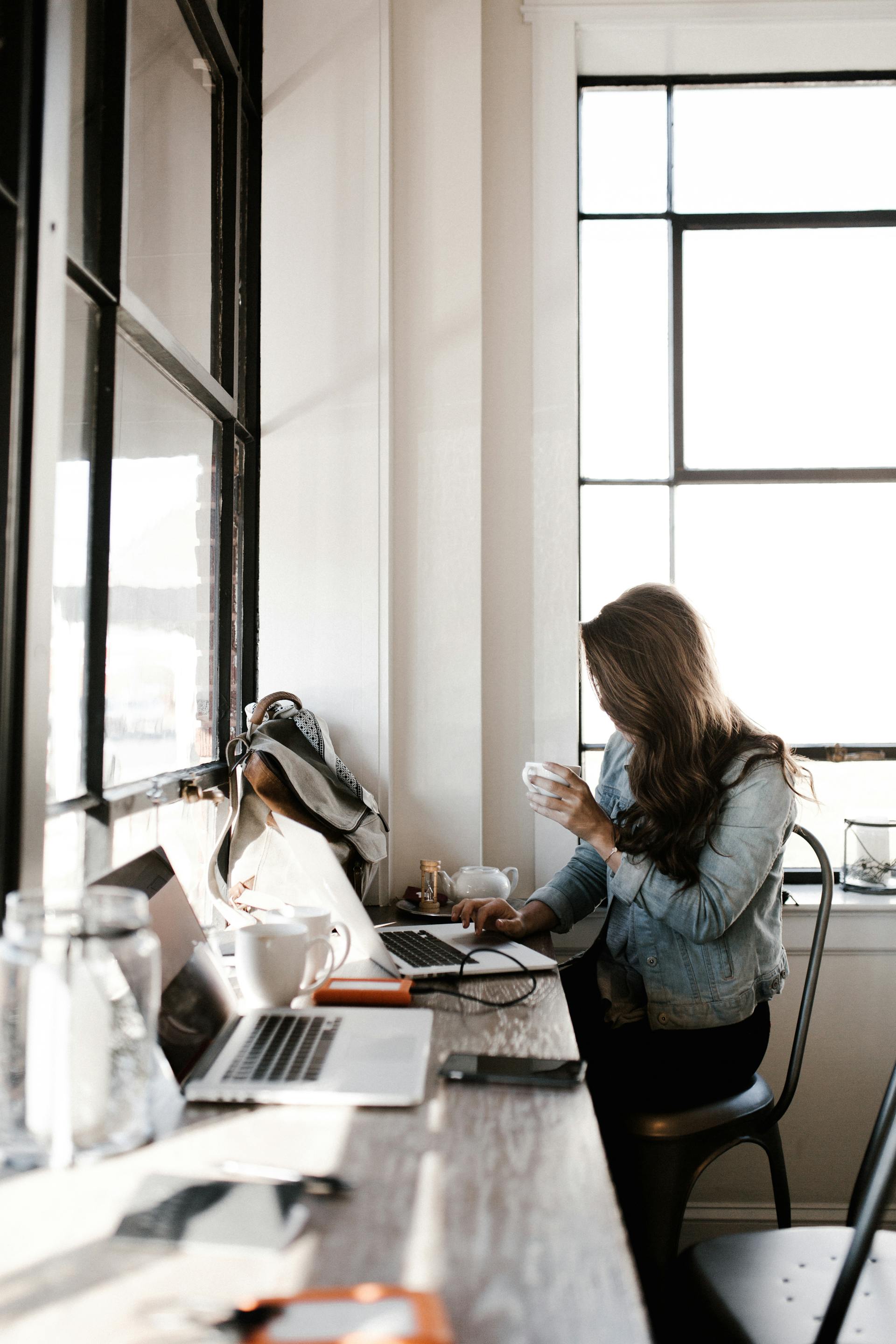 A young woman working on her laptop while sitting beside a desk | Source: Pexels