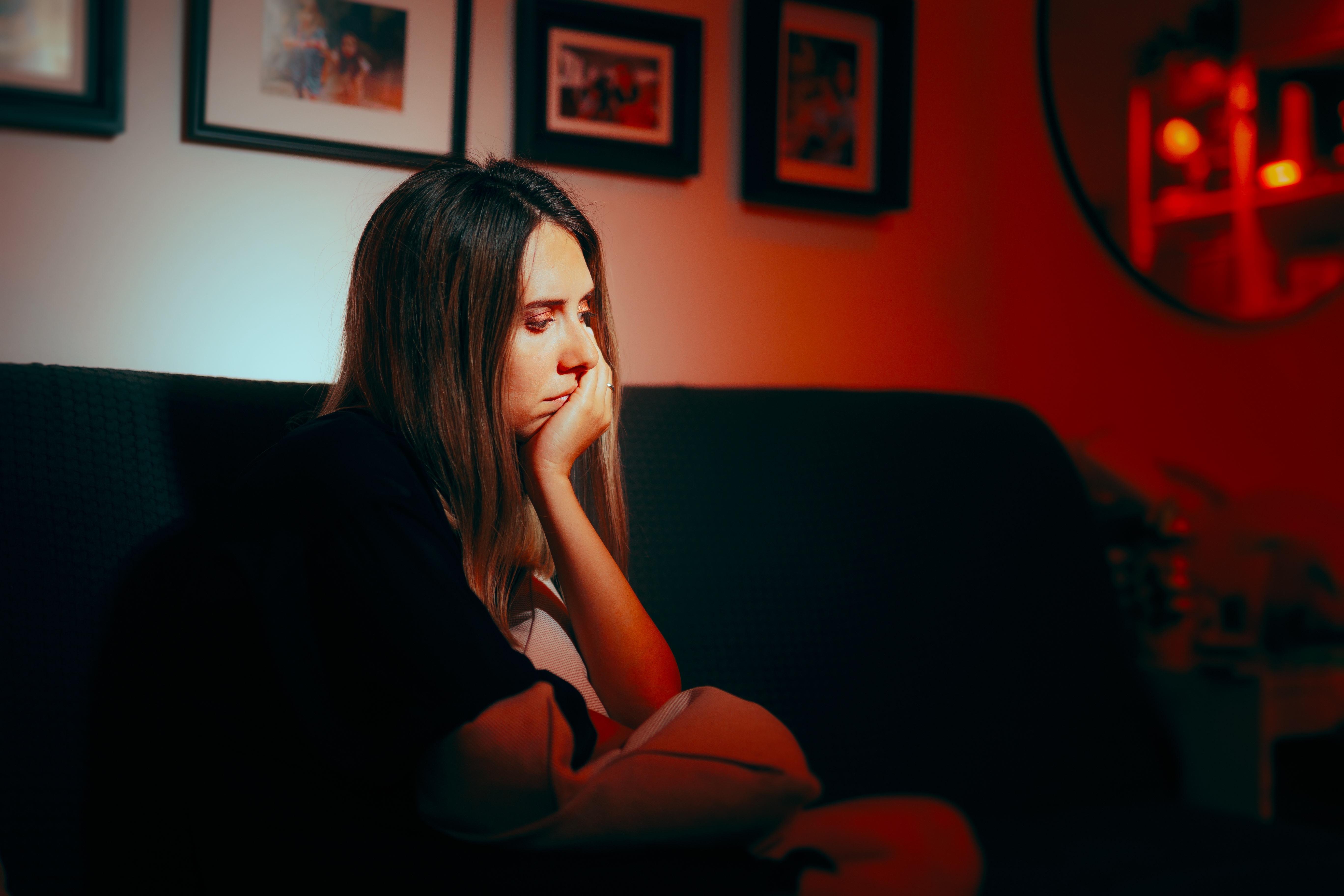 A distressed woman sitting on the couch | Source: Shutterstock