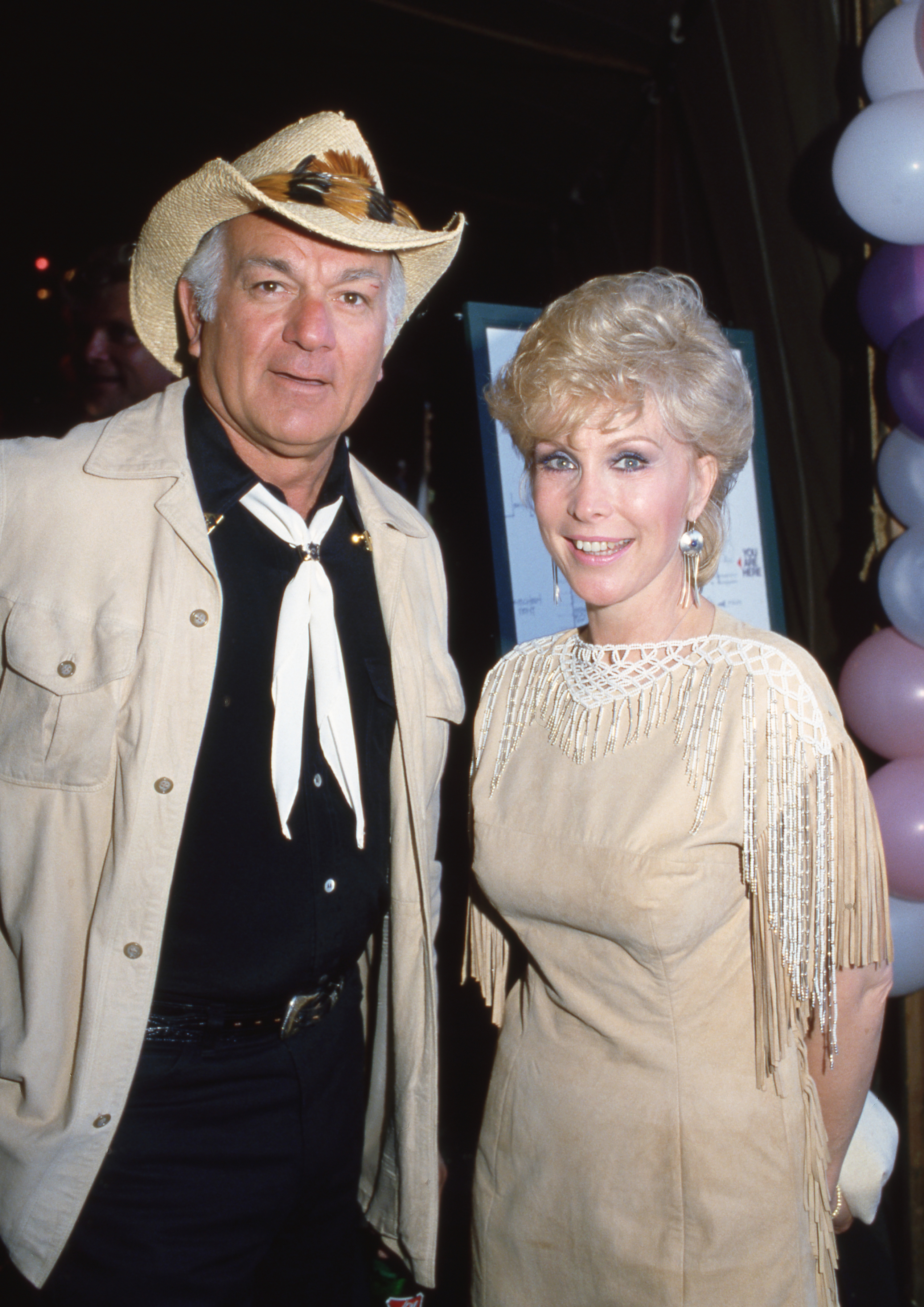 Barbara Eden wears a cream and white outfit beside Robert Mandan at a party in 1982. | Source: Getty Images