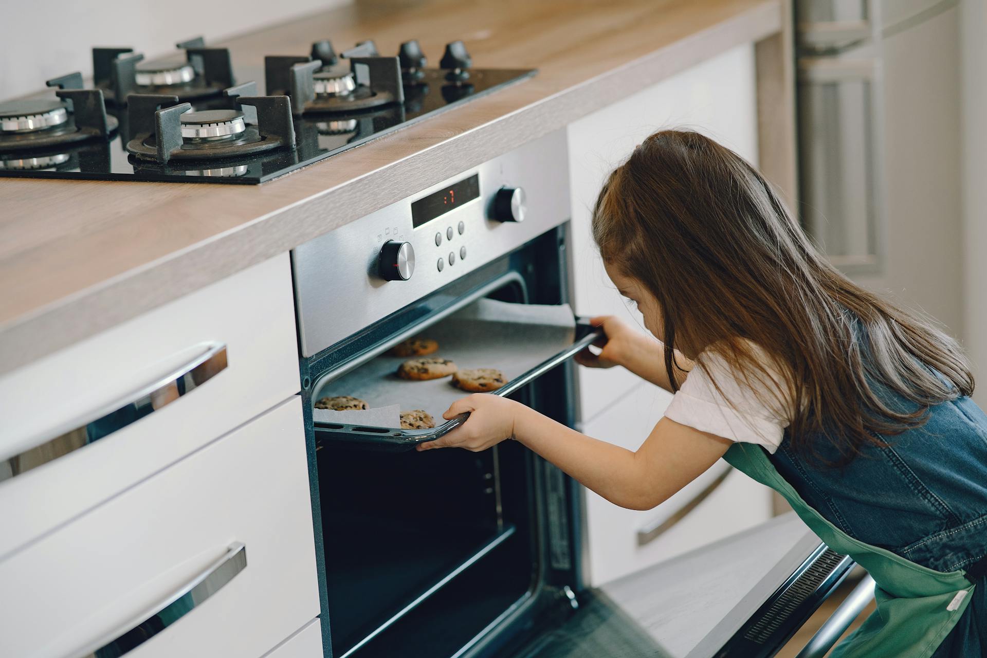 A girl putting a tray of cookies in the oven | Source: Pexels