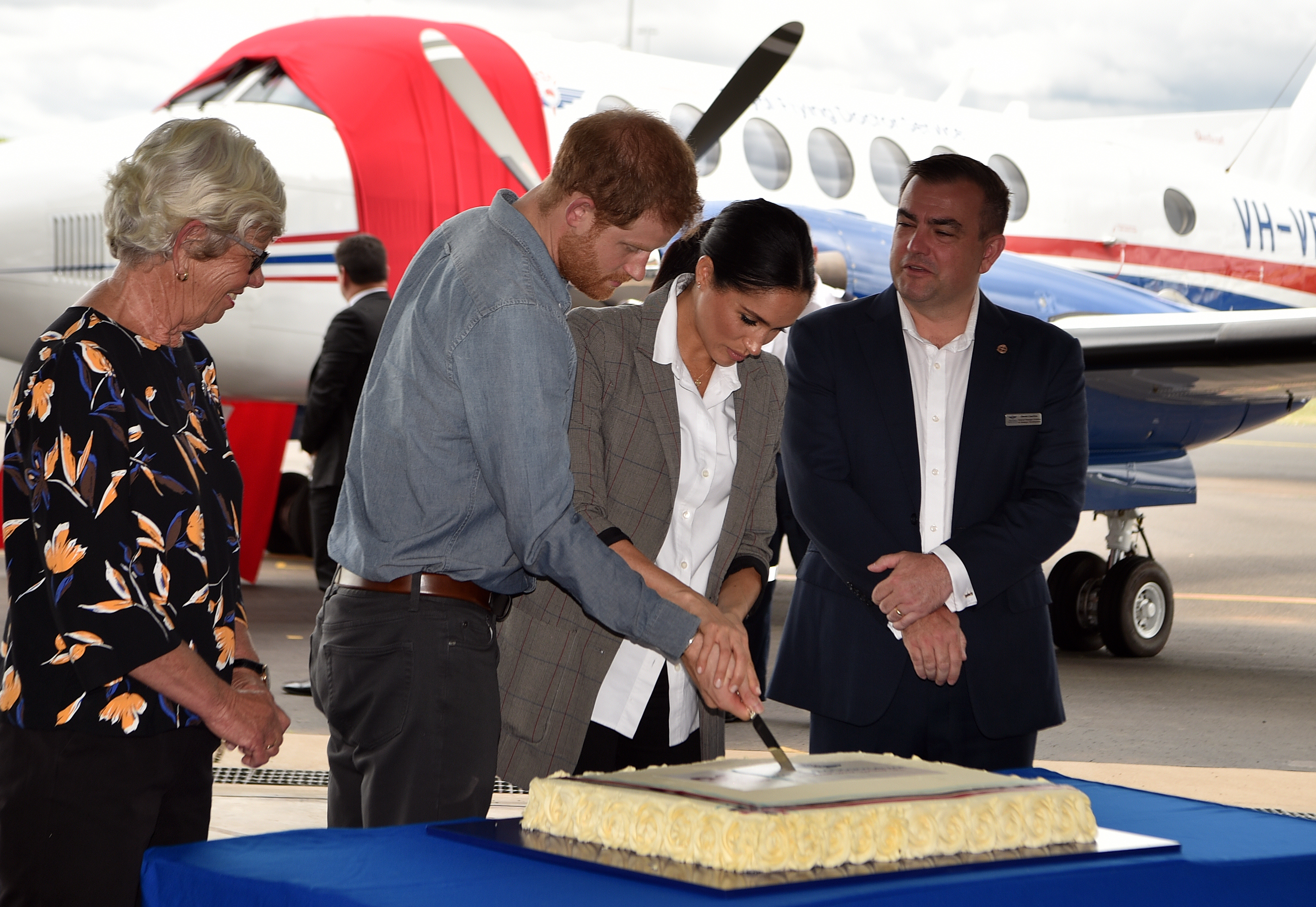 Prince Harry and Meghan Markle cutting an anniversary cake commemorating the 90 years of Australia's Royal Flying Doctor Service at Dubbo Regional Airport, Australia on October 17, 2018 | Source: Getty Images