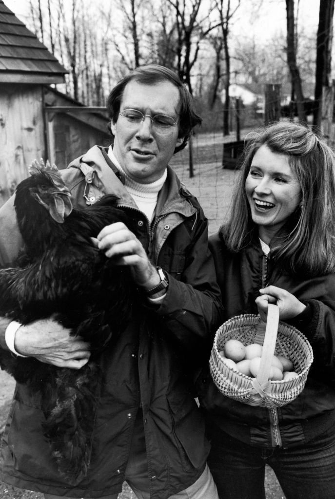 Publisher Andy Stewart holding a black Cochin hen and wife, caterer Martha, holding a basket of eggs in barnyard of their home | Getty Images