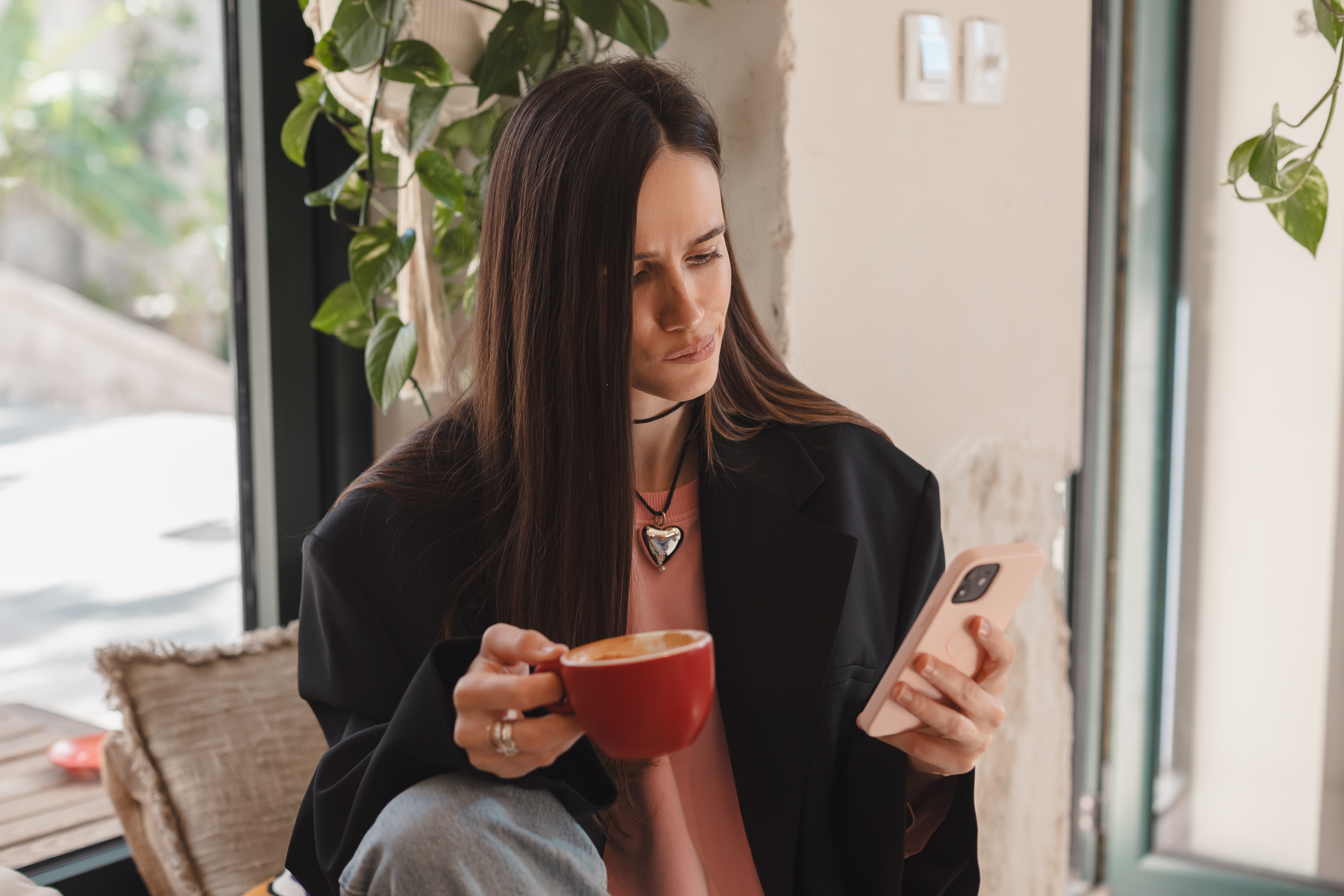 A woman using her phone while holding a cup of coffee | Source: Shutterstock