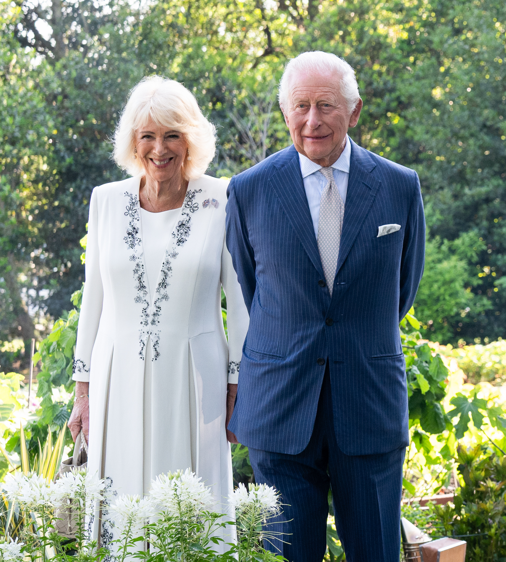 King Charles III and Queen Camilla were photographed standing together in a garden setting at the White House on 27 April 2026 in Washington, D.C., smiling gently as they posed among greenery and white blooms during the afternoon tea hosted in their honour. The relaxed yet formal portrait reflected the tone of the early engagements, blending royal poise with the softer atmosphere of the outdoor reception.