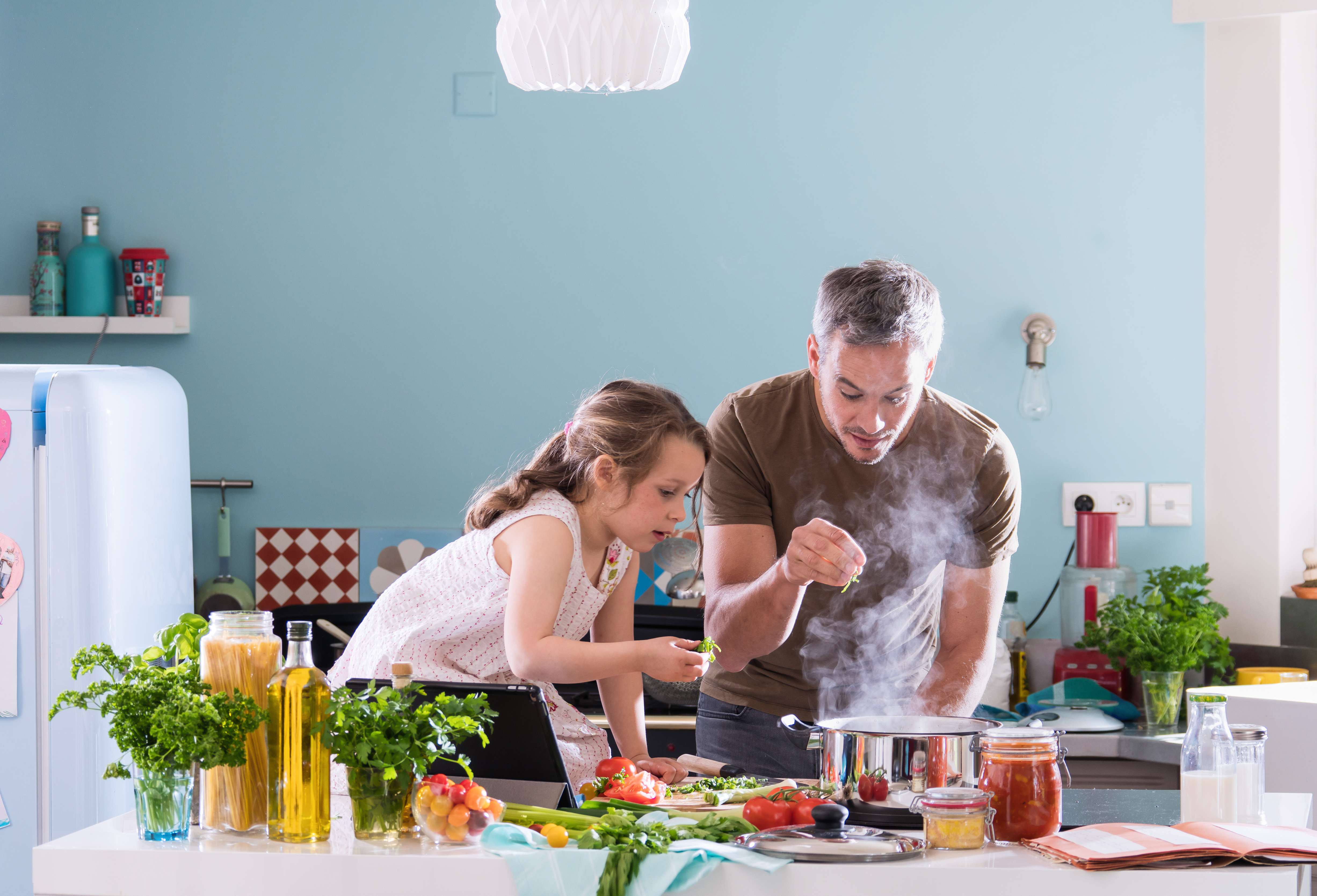 Daddy cooking food with his little girl in the kitchen | Source: Shutterstock