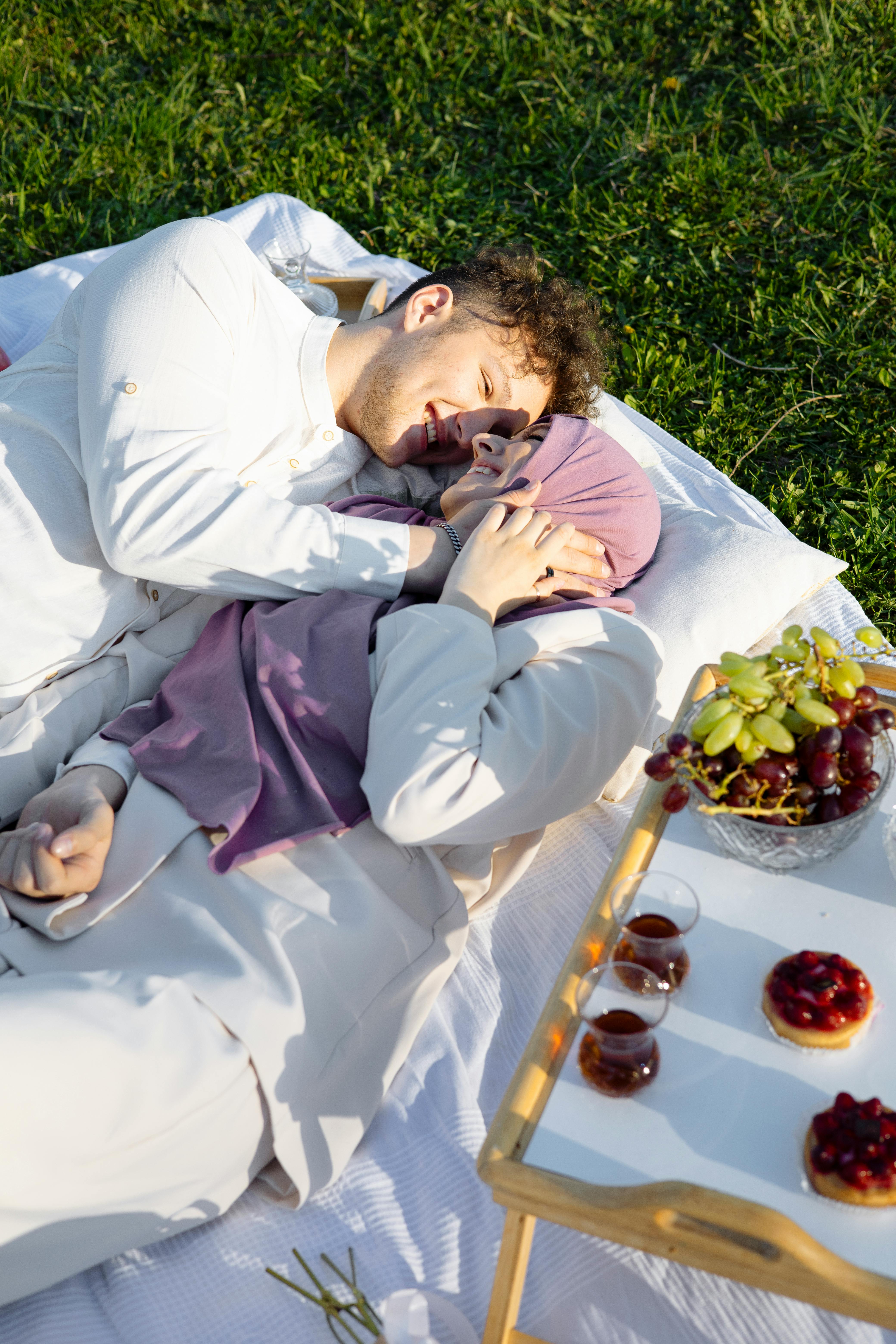 A couple having a romantic moment while lying down with drinks and grapes beside them | Source: Pexels