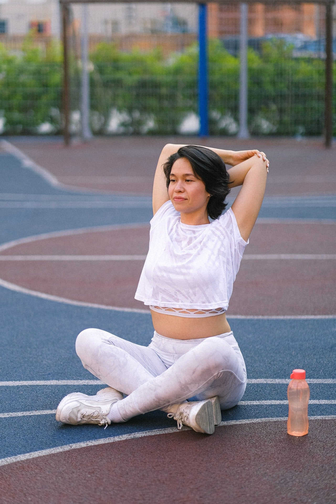 Una mujer joven hace ejercicios sentada en el suelo. | Foto: Pexels
