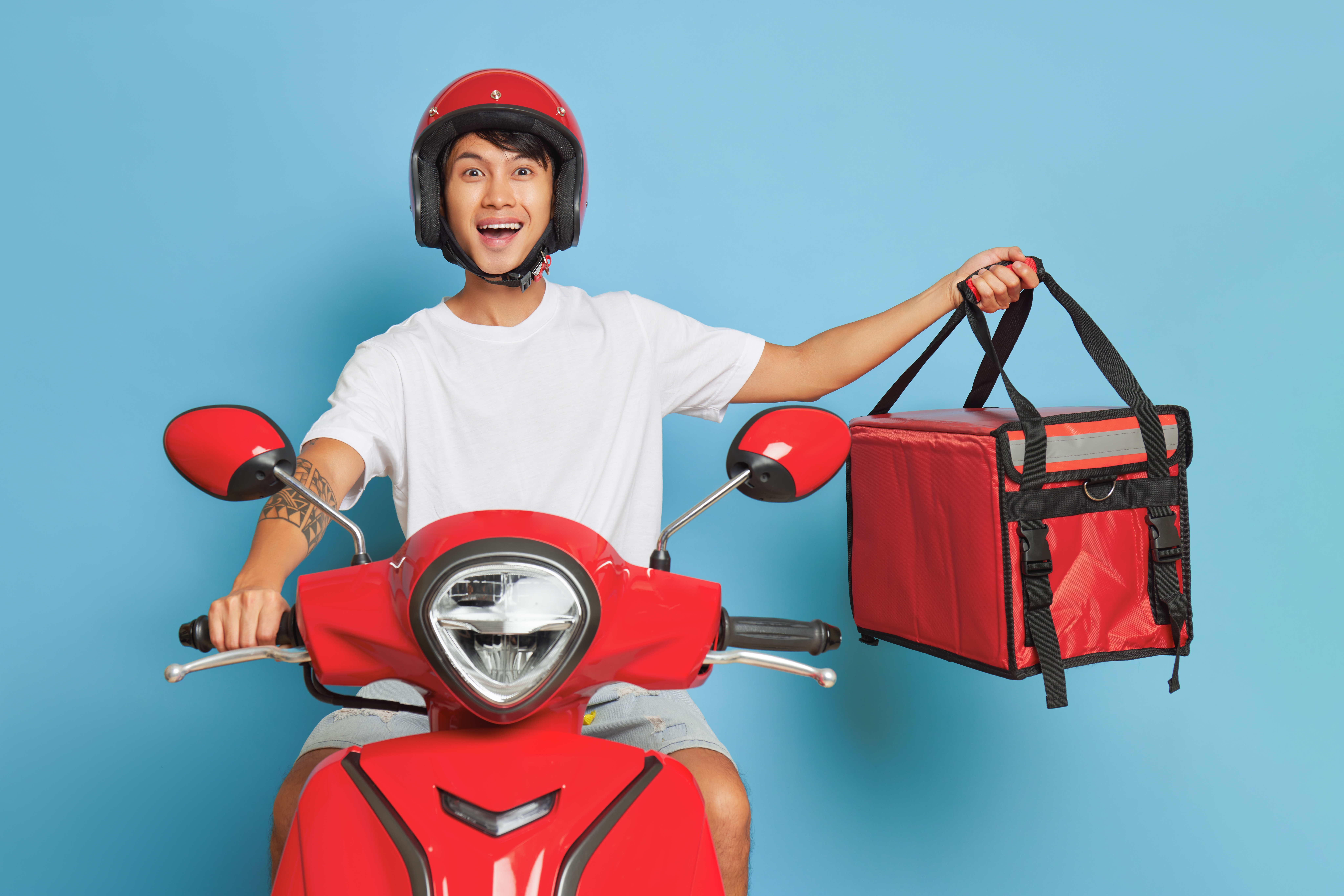 An asian delivery driver holding out a red bag | Source: Shutterstock