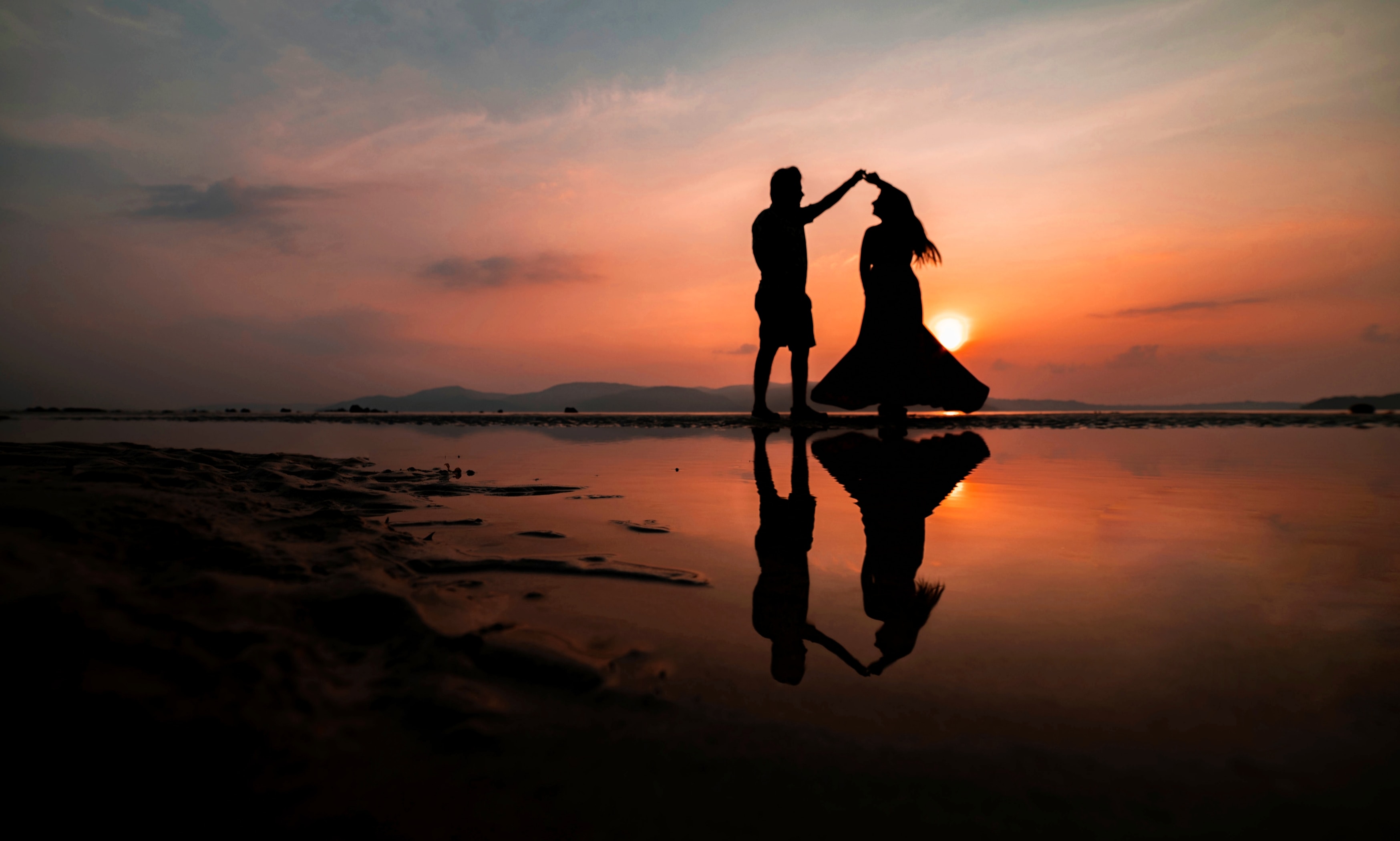 Silhouette of man and woman on a beach during sunset. | Source: Unsplash