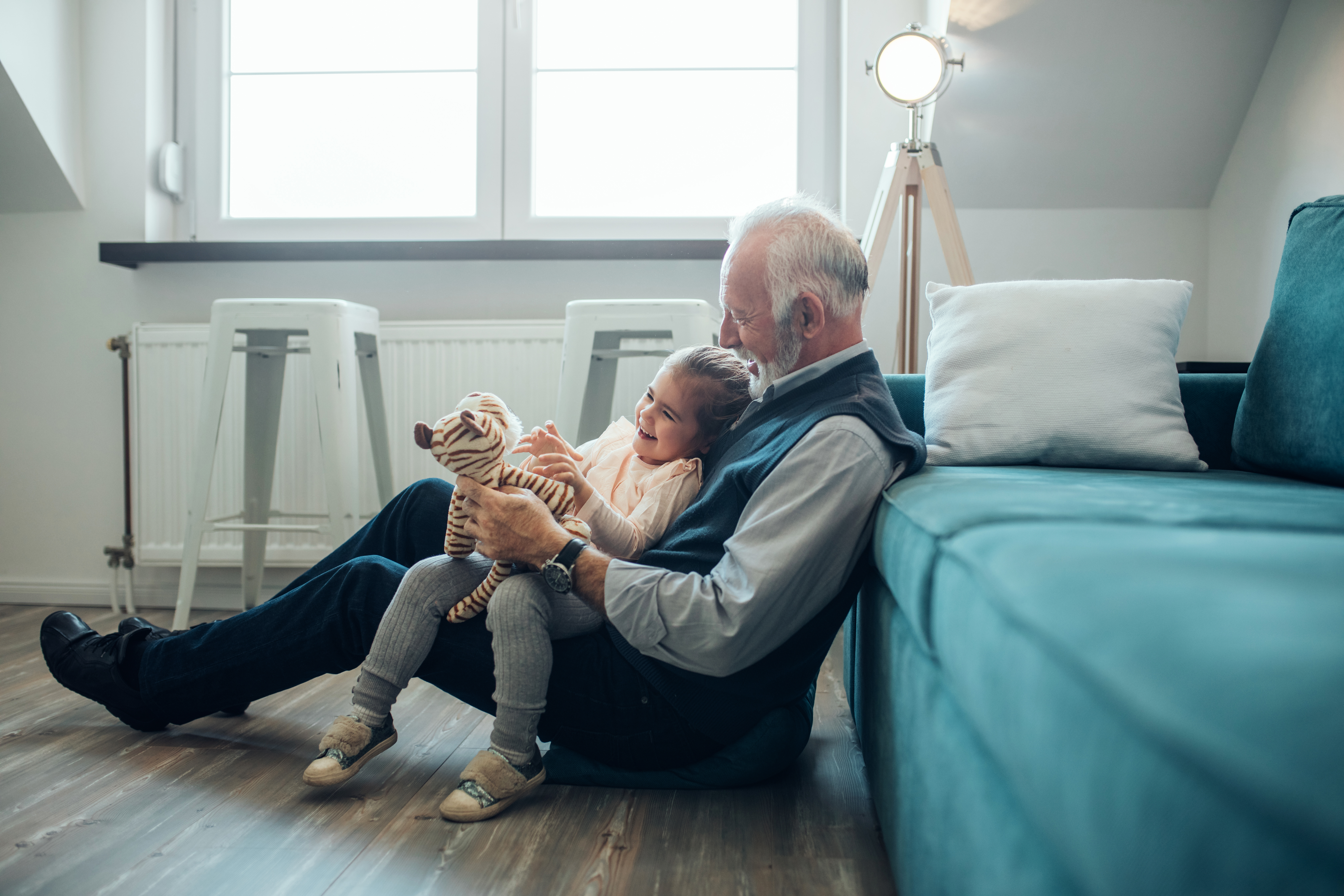 A grandfather sitting on the floor with his granddaughter in his lap | Source: Shutterstock