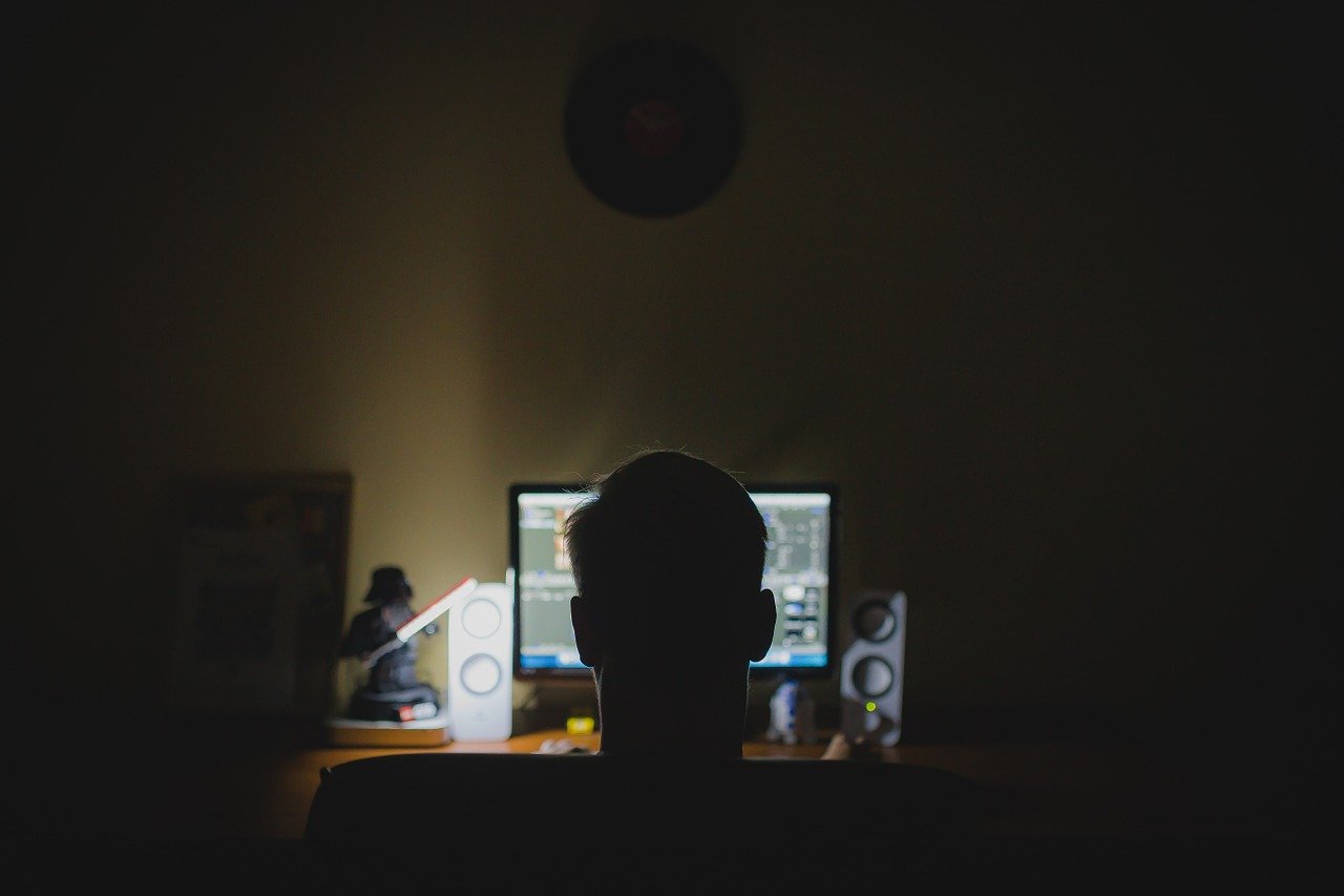 Hombre trabajando frente a la computadora en las sombras. | Foto: Pixabay