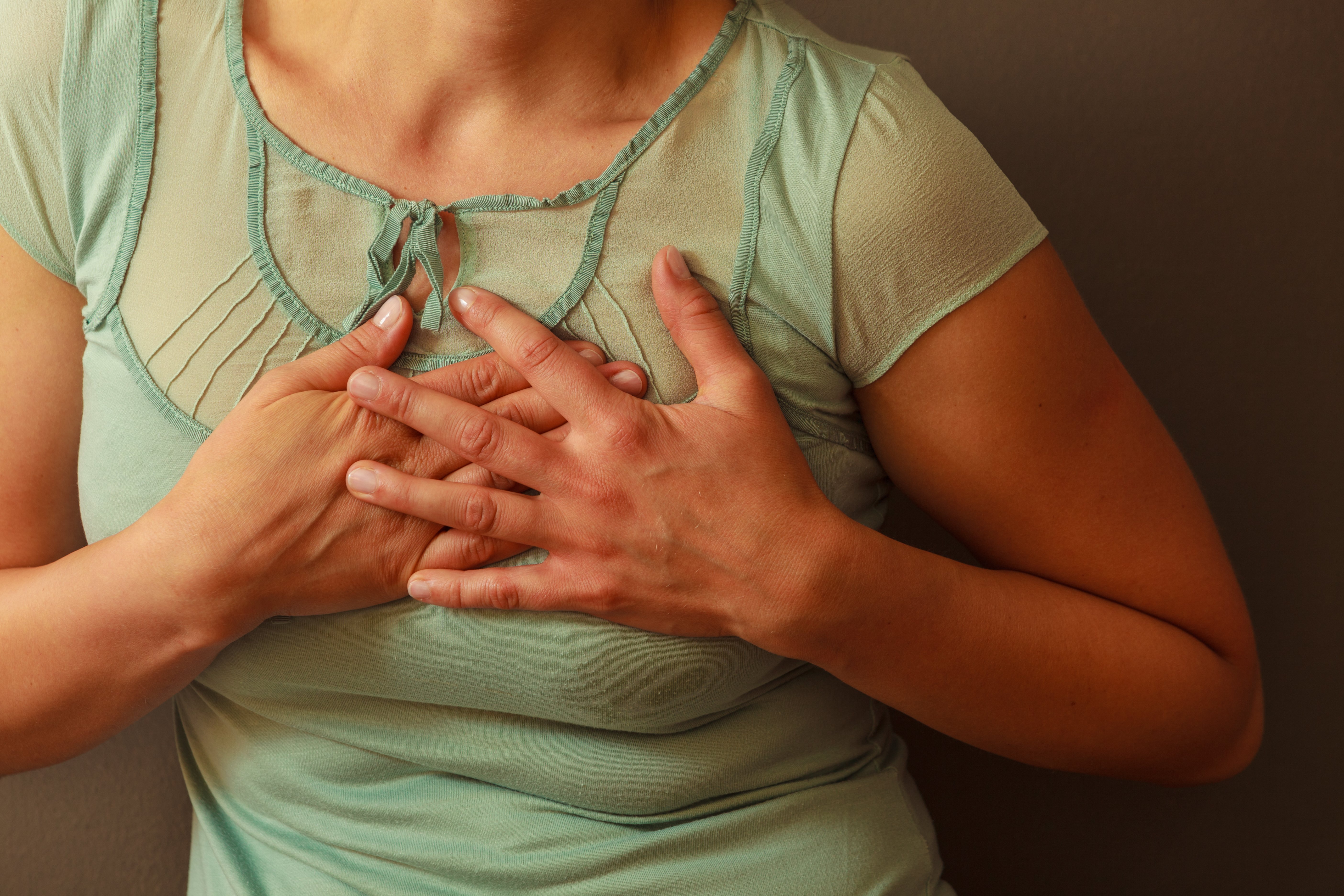 Frau greift sich an die Brust | Quelle: Shutterstock