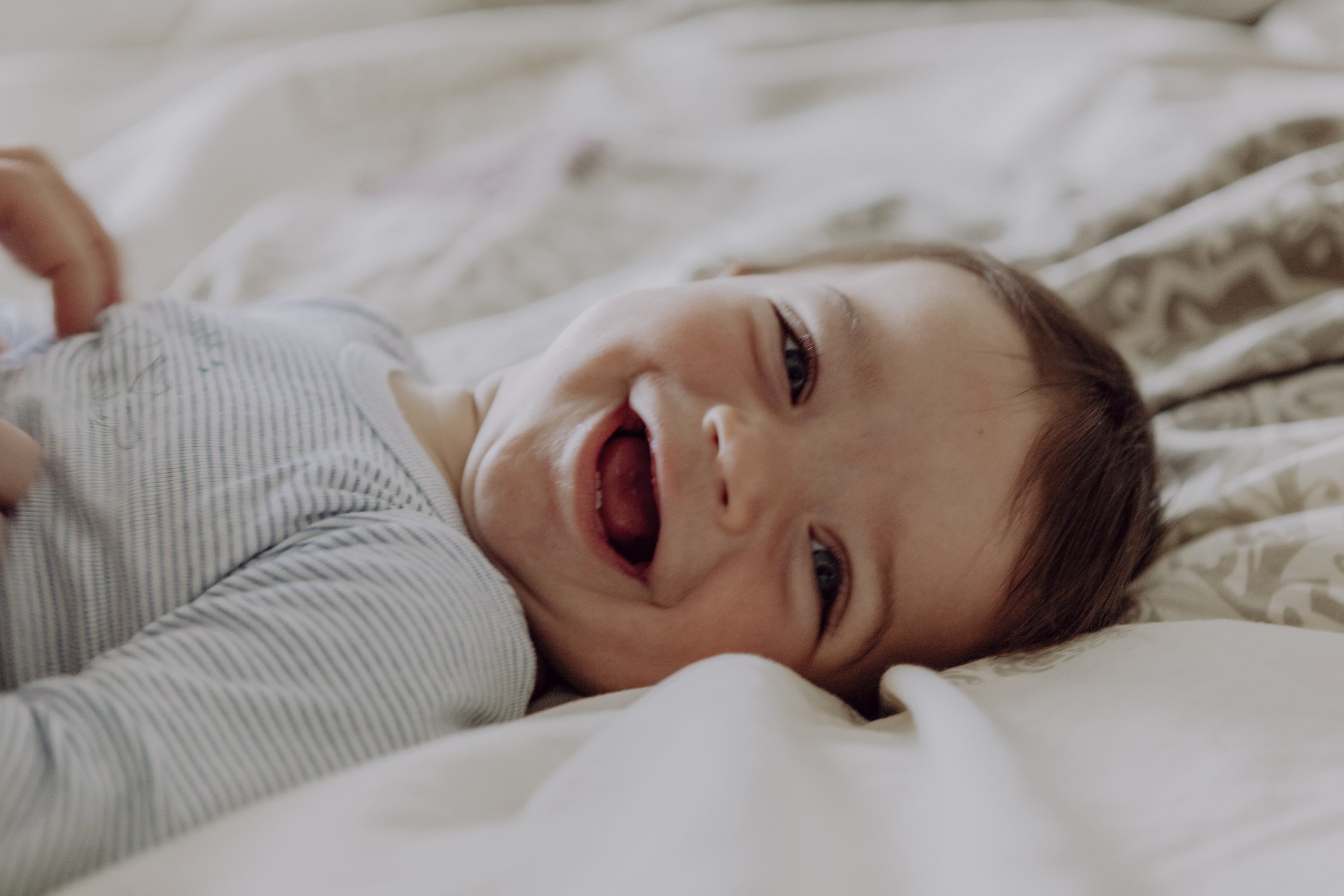 A portrait picture of a baby happily laughing lying on the bed. | Photo: Getty Images 