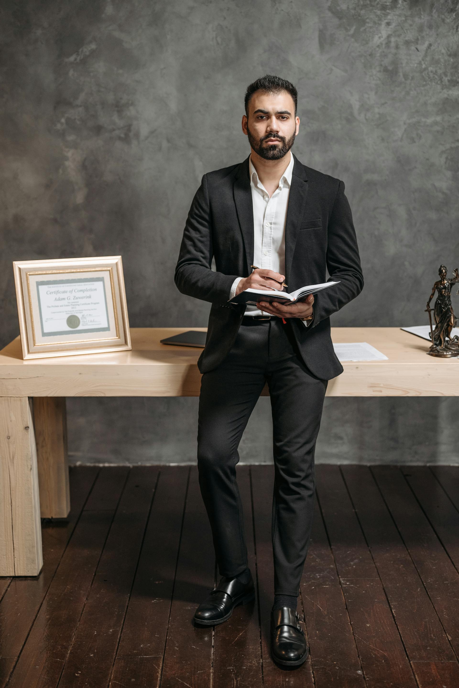 Man in a black suit holding a notebook | Source: Pexels