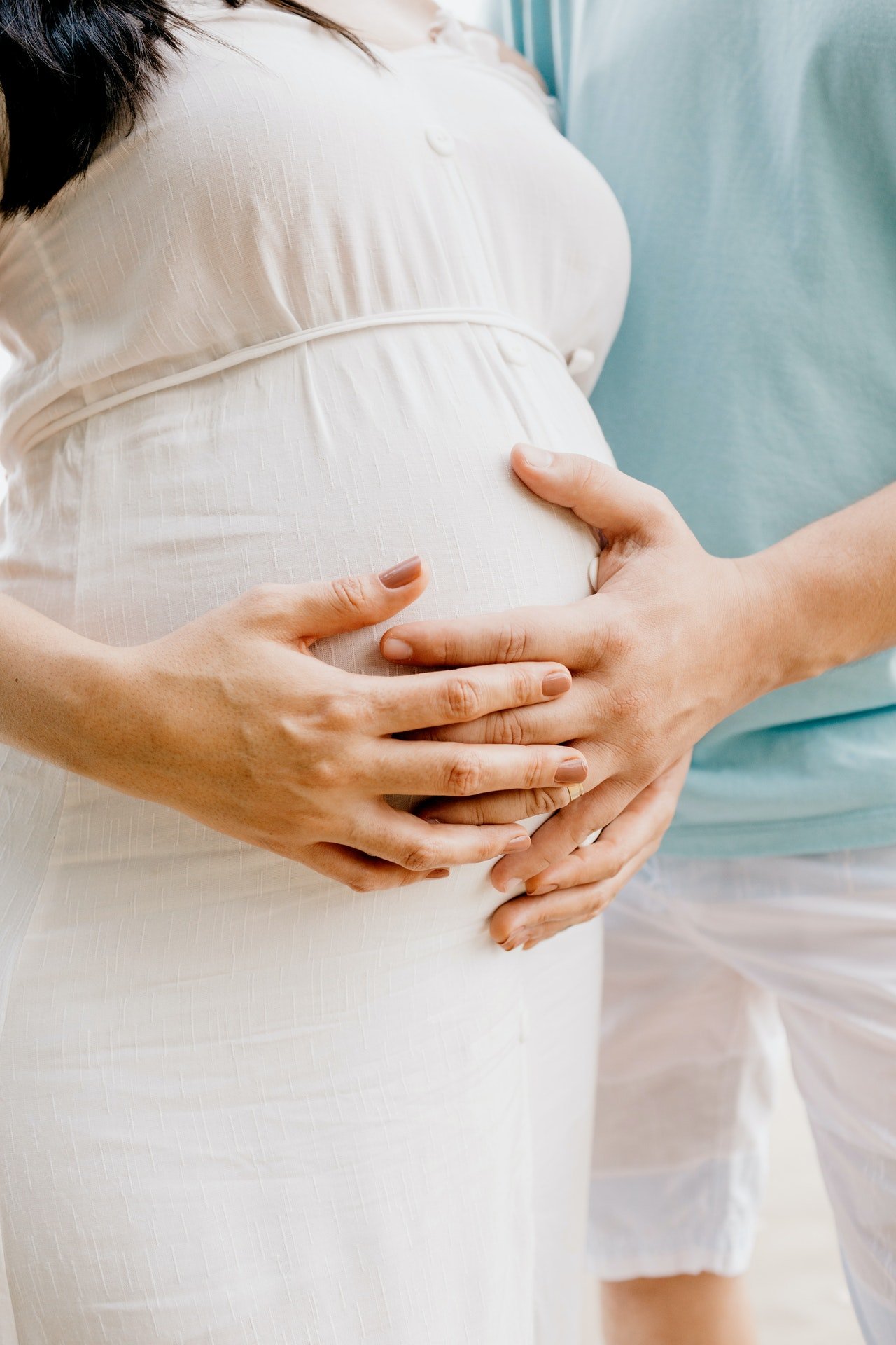 Man and pregnant woman's hands cradling her belly. | Source: Pexels/Jonathan Borba