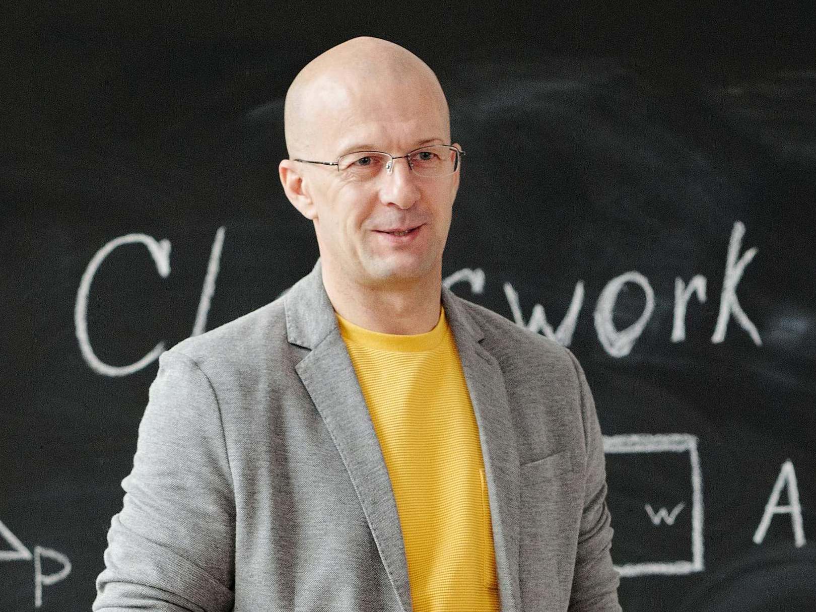 A man standing in front of a classroom chalkboard, in conversation | Source: Pexels