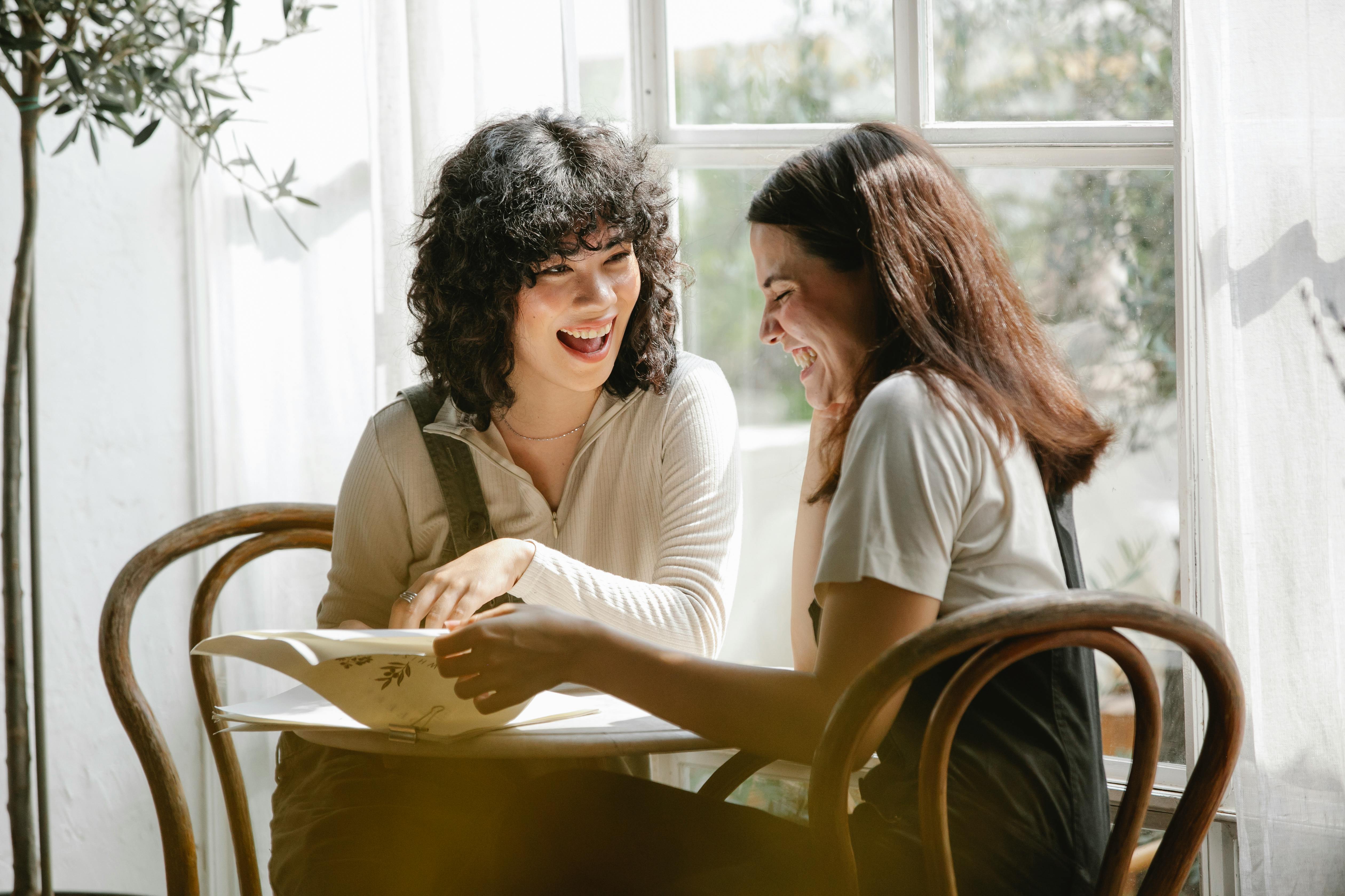 Two women laughing while looking at paperwork | Source: Pexels