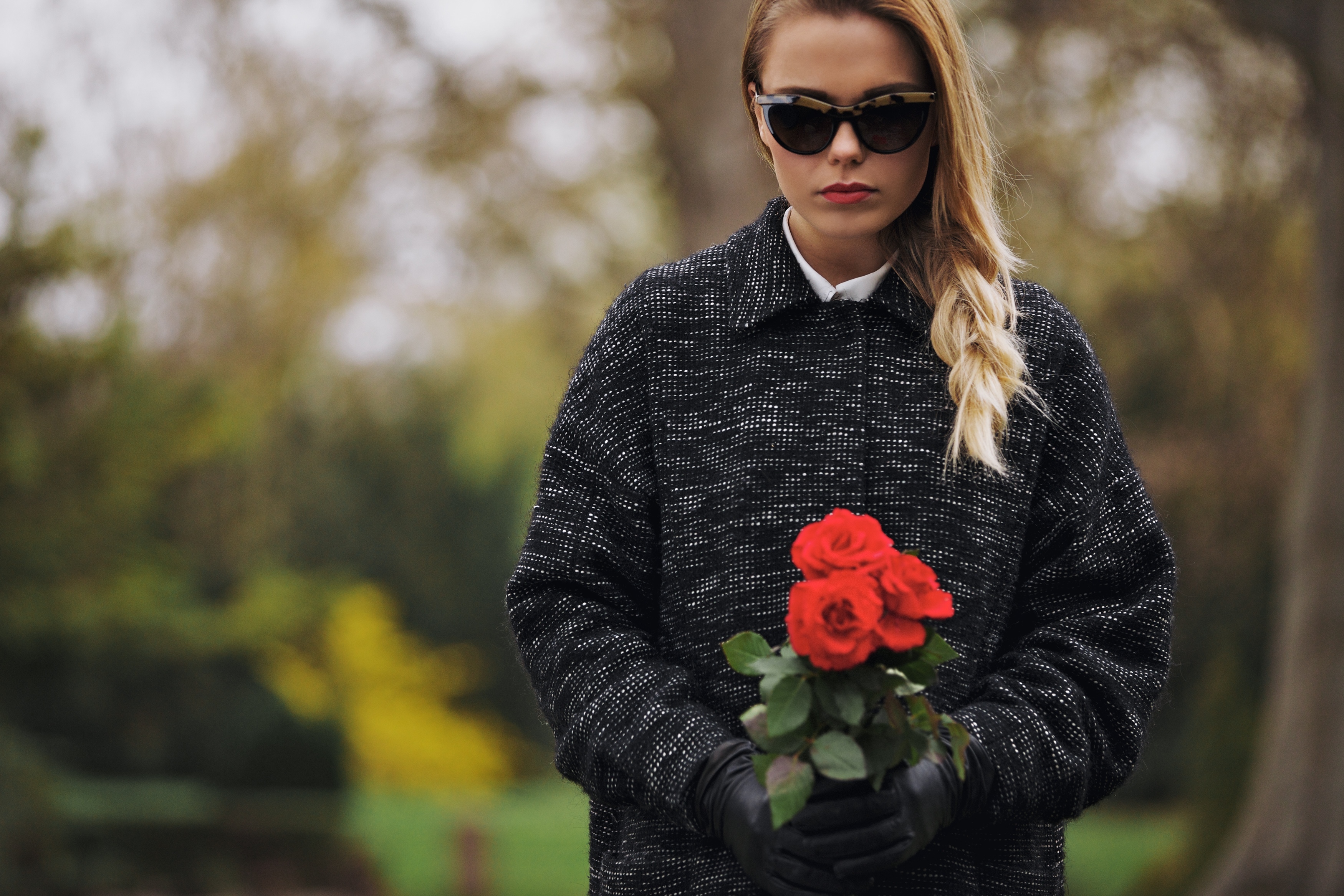 Portrait of young woman in black dress at graveyard holding fresh flowers. | Source: Shutterstock