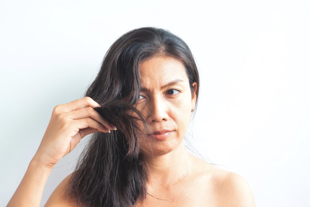 Mujer preocupada por su cabello dañado. | Foto: Shutterstock