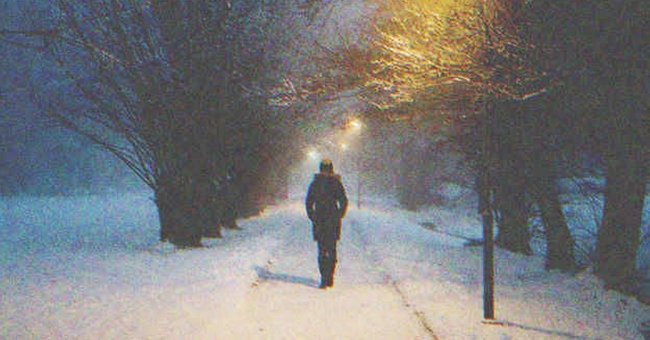 A man walking at night on a snowy road | Source: Shutterstock