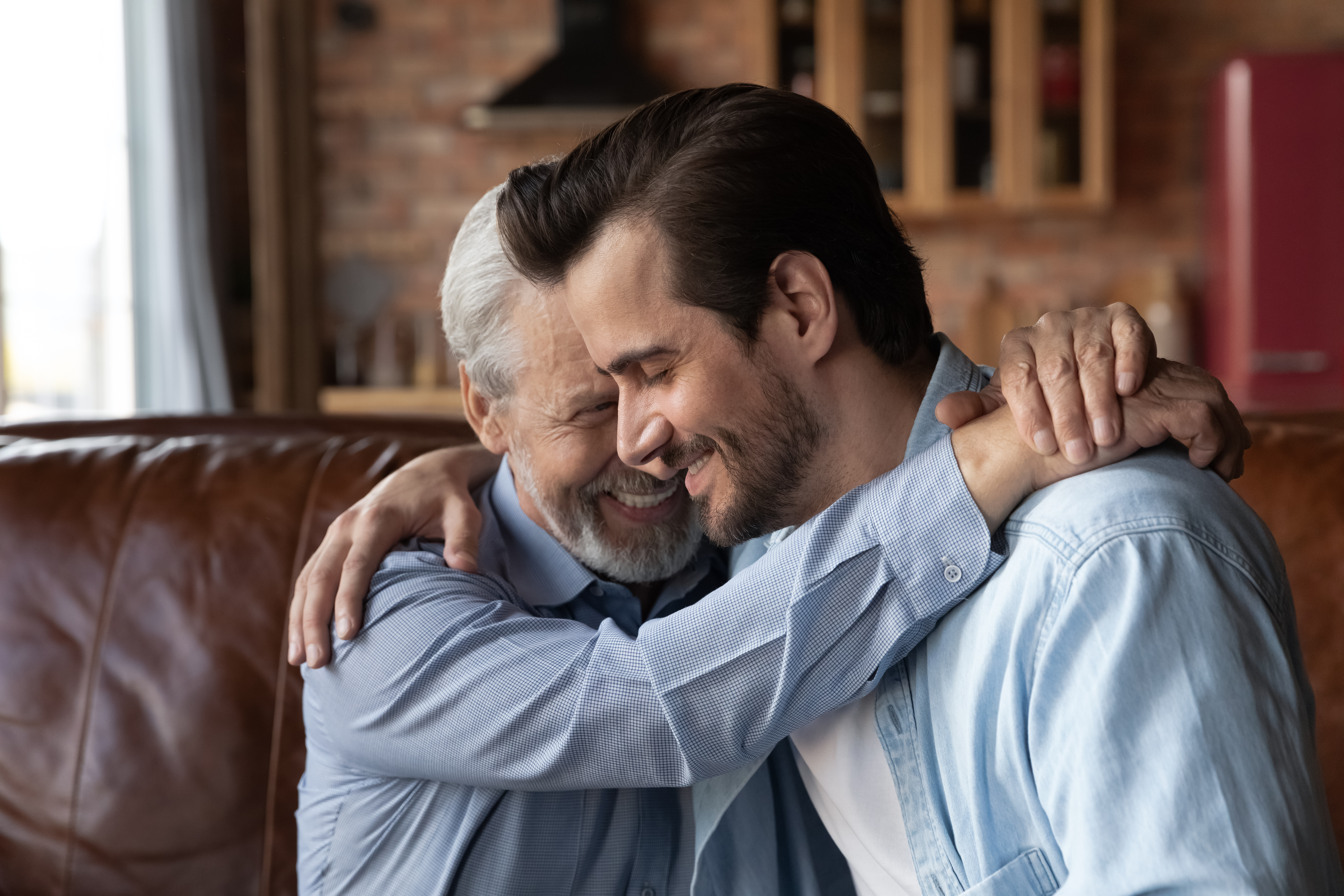 An happy older man hugging a younger one | Source: Shutterstock