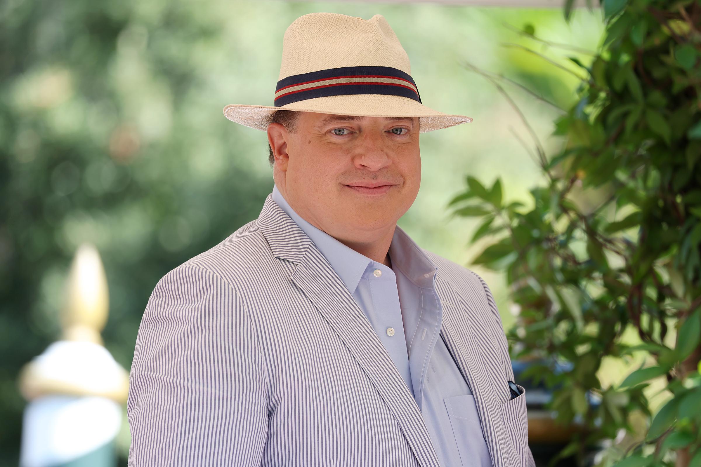 Brendan Fraser poses in a cream hat, light blue shirt, and pale striped blazer after arriving at the Hotel Excelsior during the 79th Venice International Film Festival in Venice, Italy.